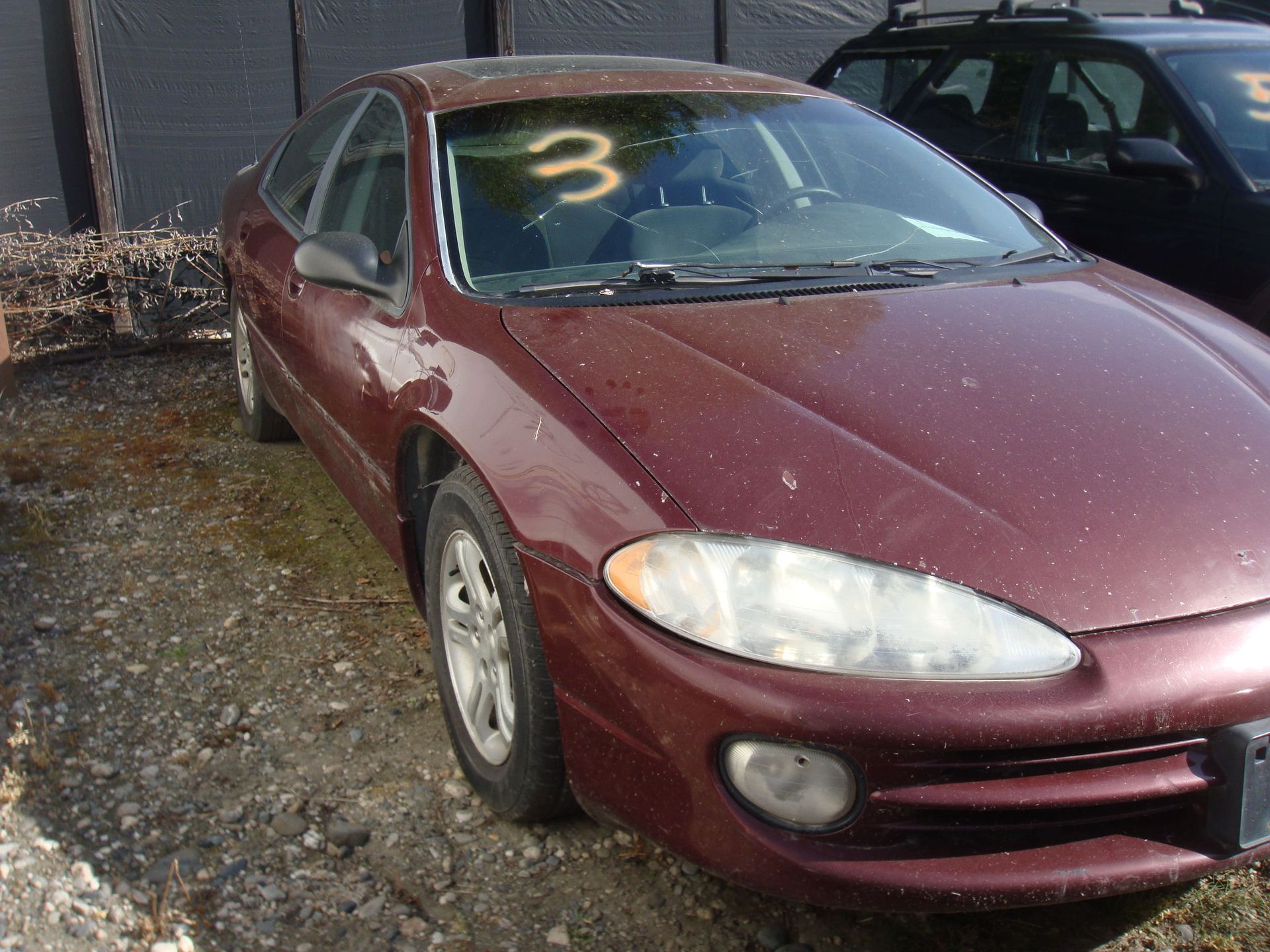 Maroon sedan parked in a driveway with a large yellow “3” on the windshield