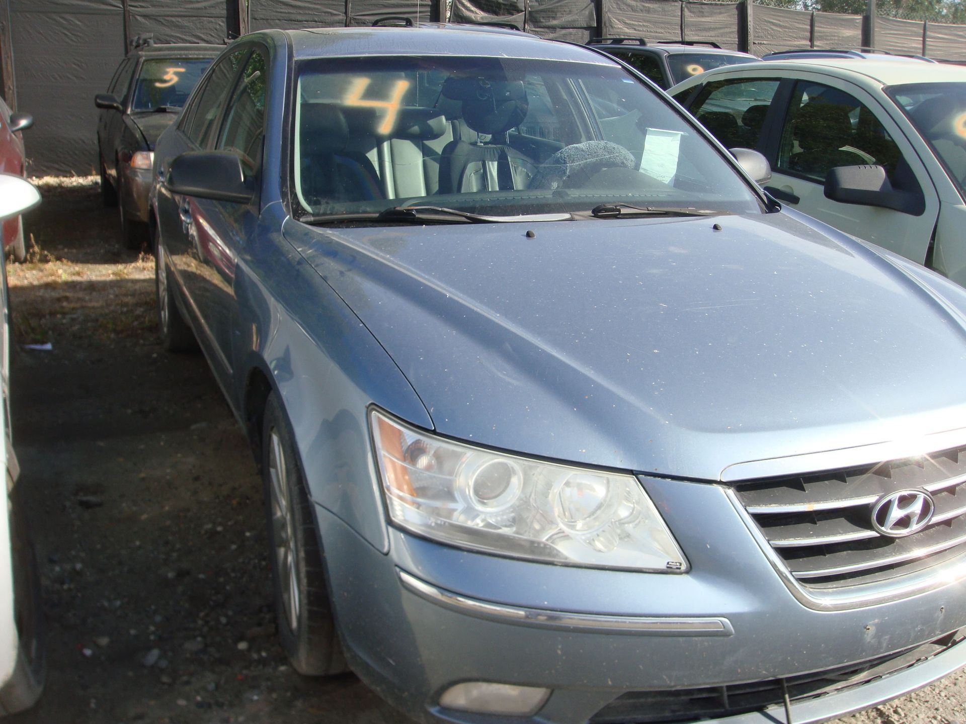 Blue Hyundai sedan parked in a lot with another car beside it