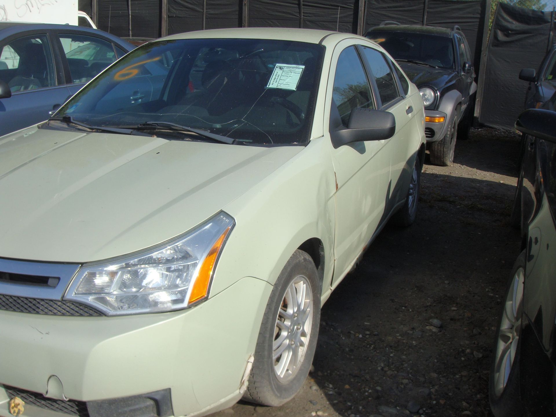 Light green sedan parked closely among other cars in a lot
