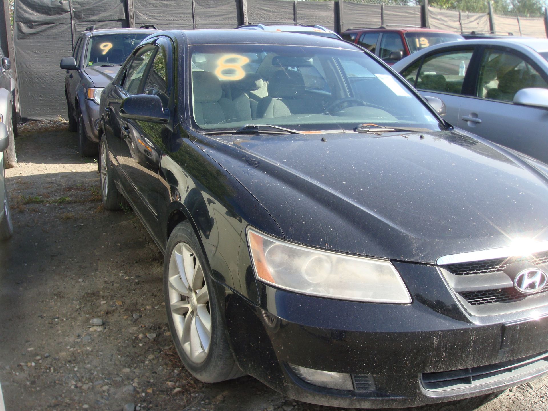 Black Hyundai sedan parked in a lot, with a yellow number 8 on the windshield