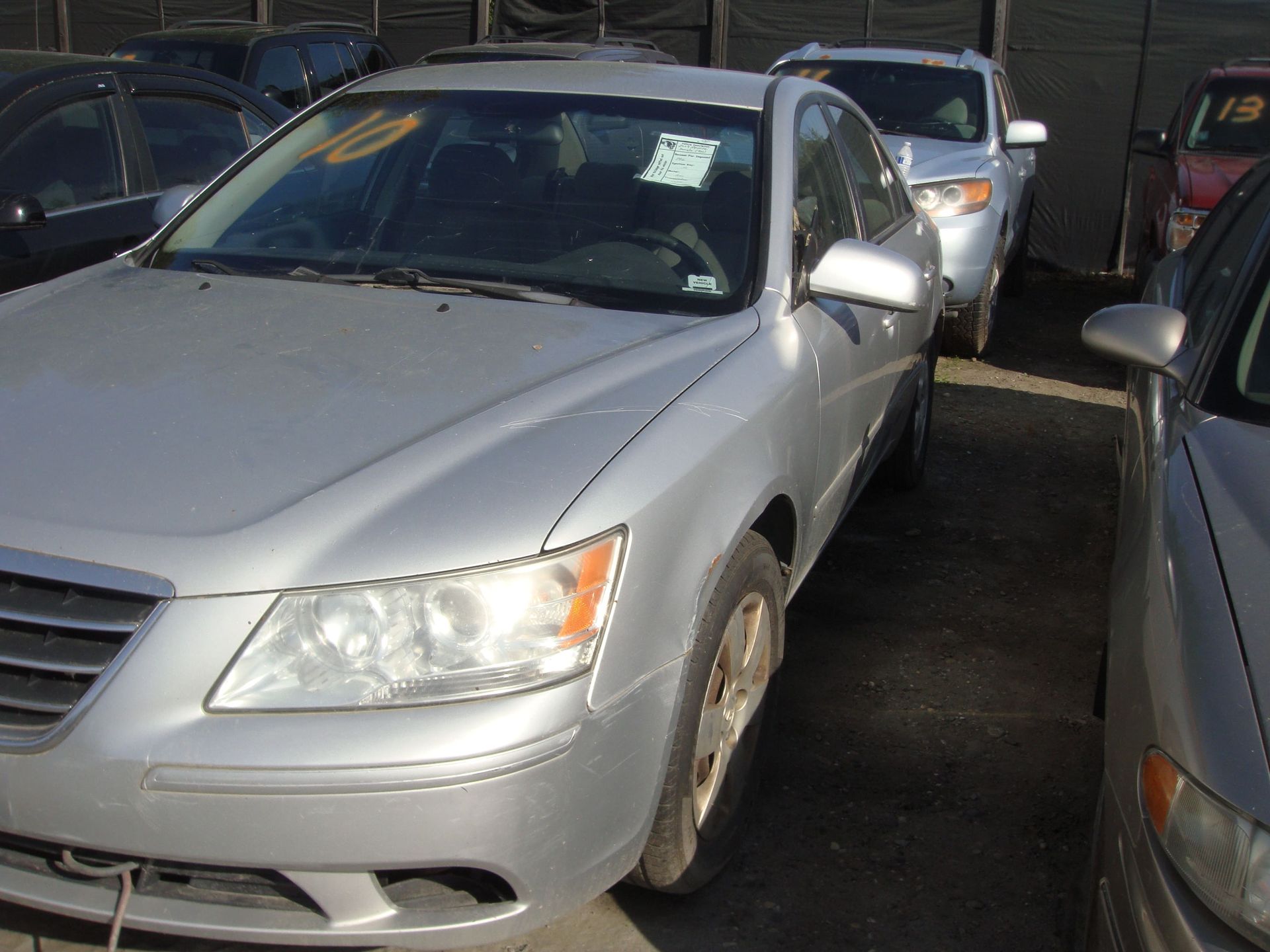 Silver sedan parked in a tight row of cars in a dim parking lot