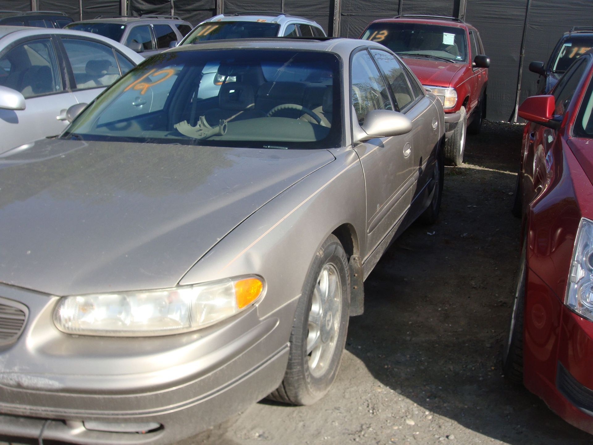 Parked silver sedan in a crowded car lot, viewed from the front-left side.