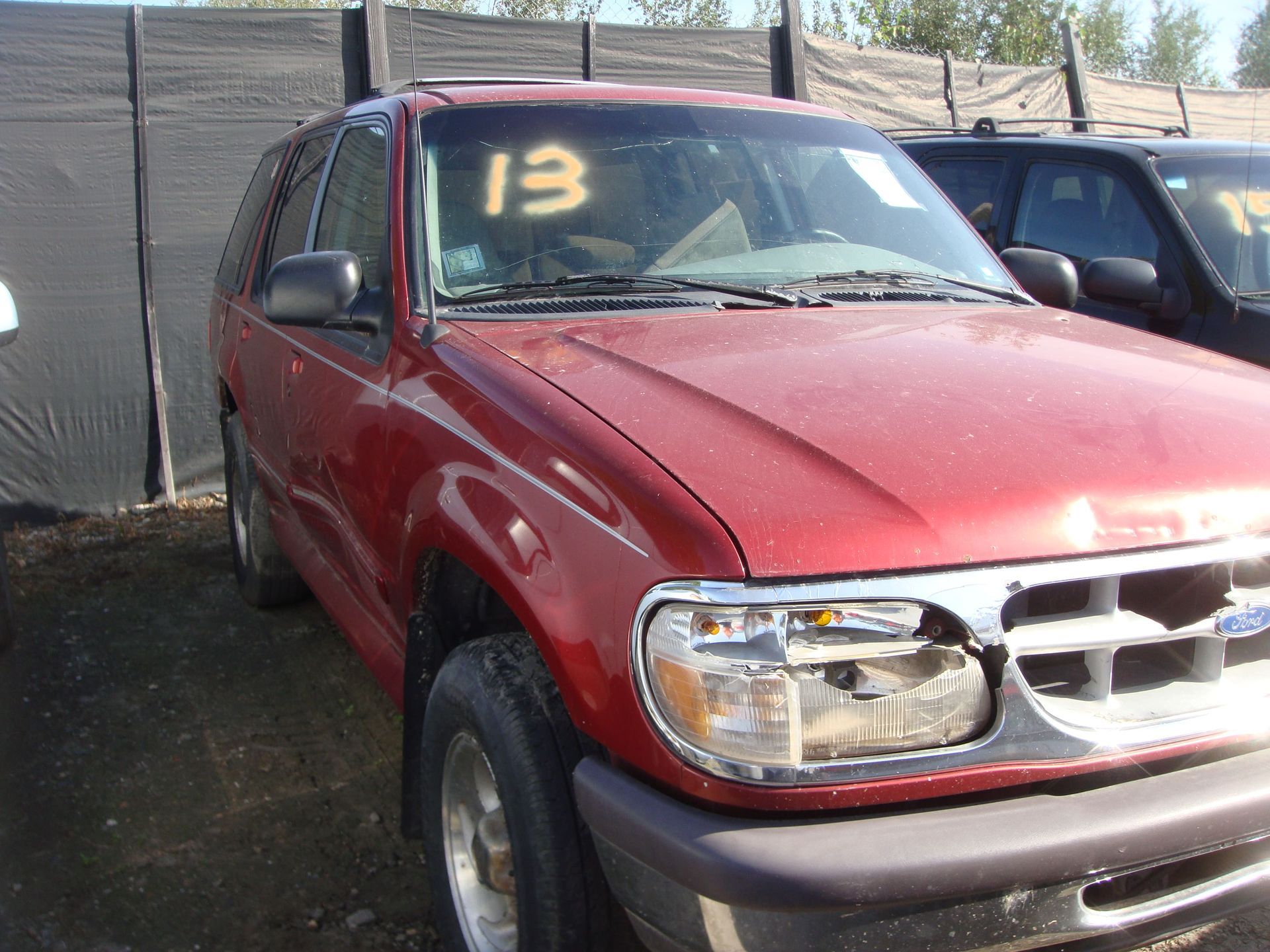 Red pickup truck parked outdoors with a yellow 13 on the windshield.