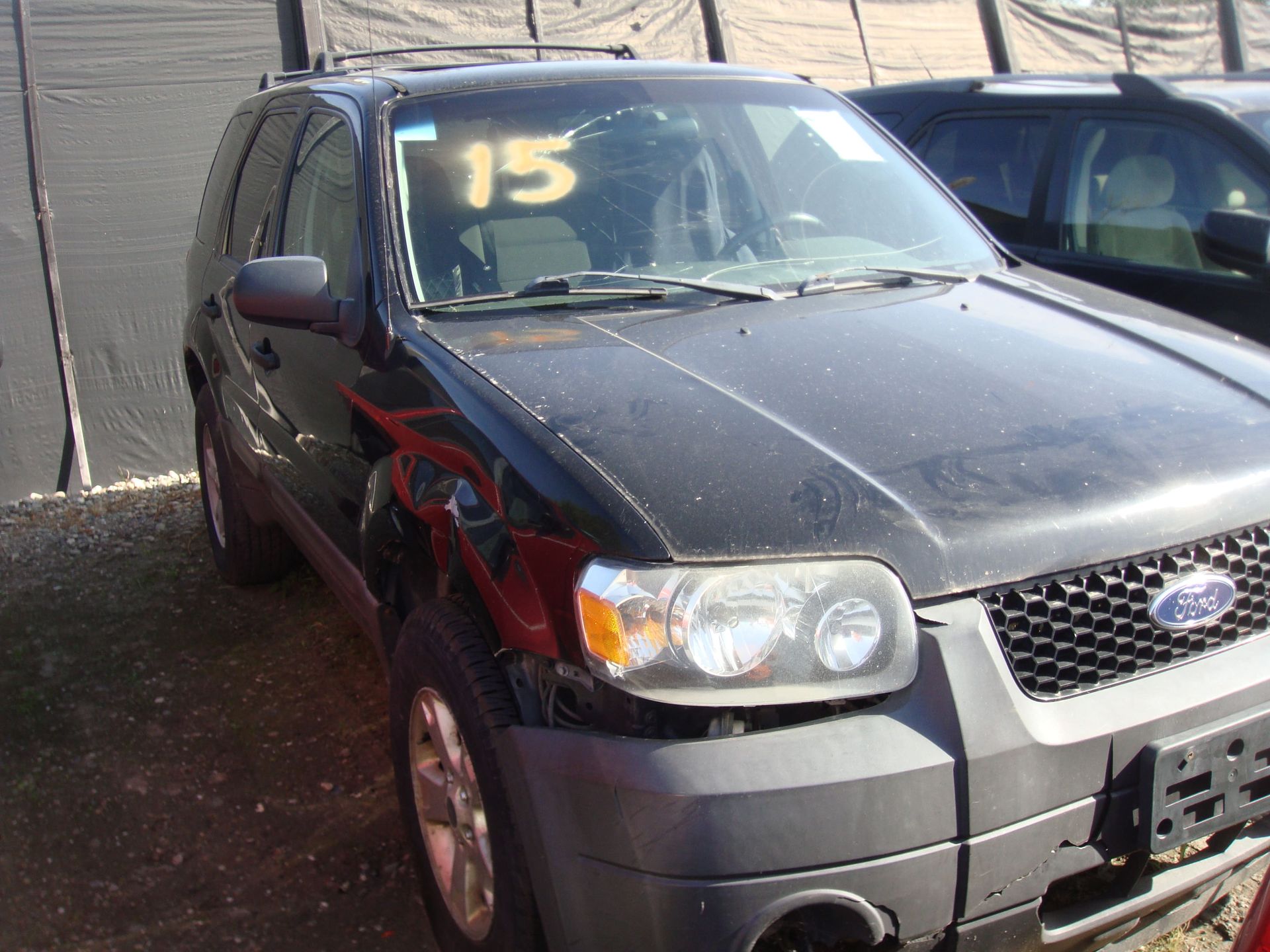 Black SUV with red damage on front side, parked outdoors near another car.