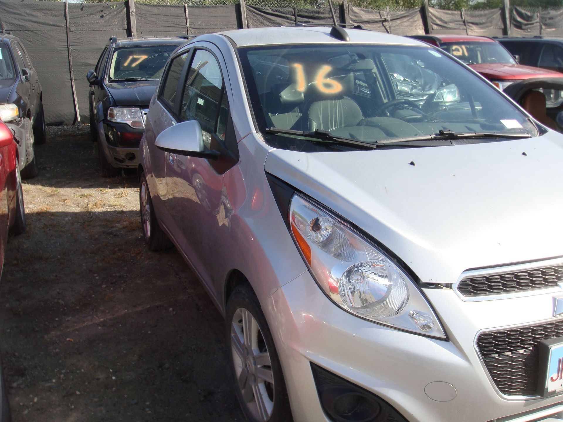 Silver compact car parked in a lot, with a large orange “16” on the windshield