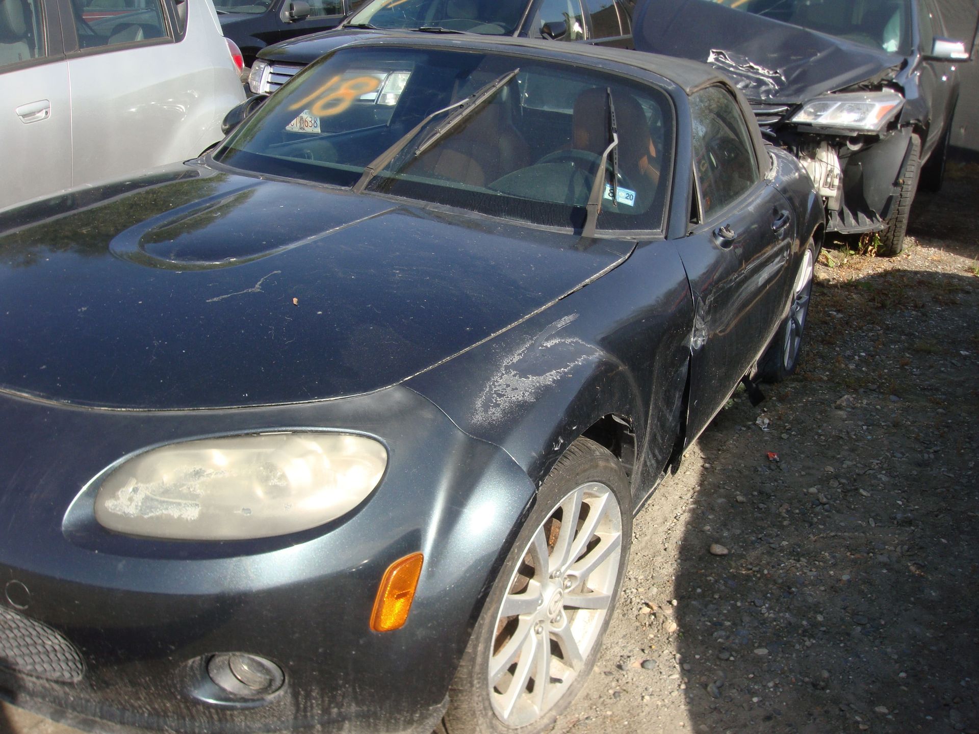 Damaged dark blue car with broken front end in a junkyard or salvage lot