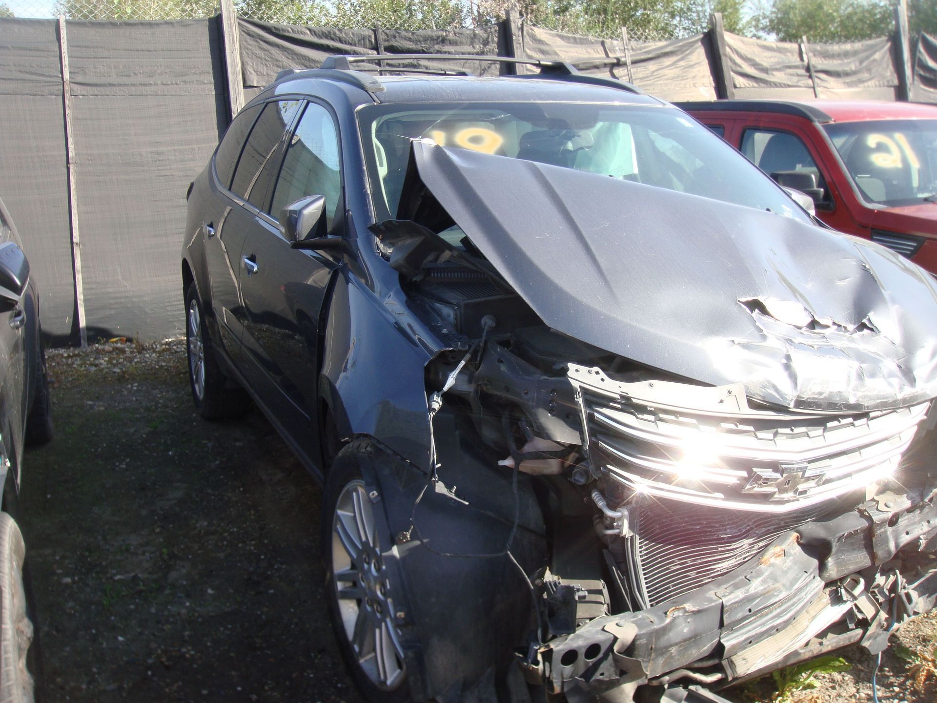 Severely damaged gray SUV with crushed front end after a crash, parked outdoors.