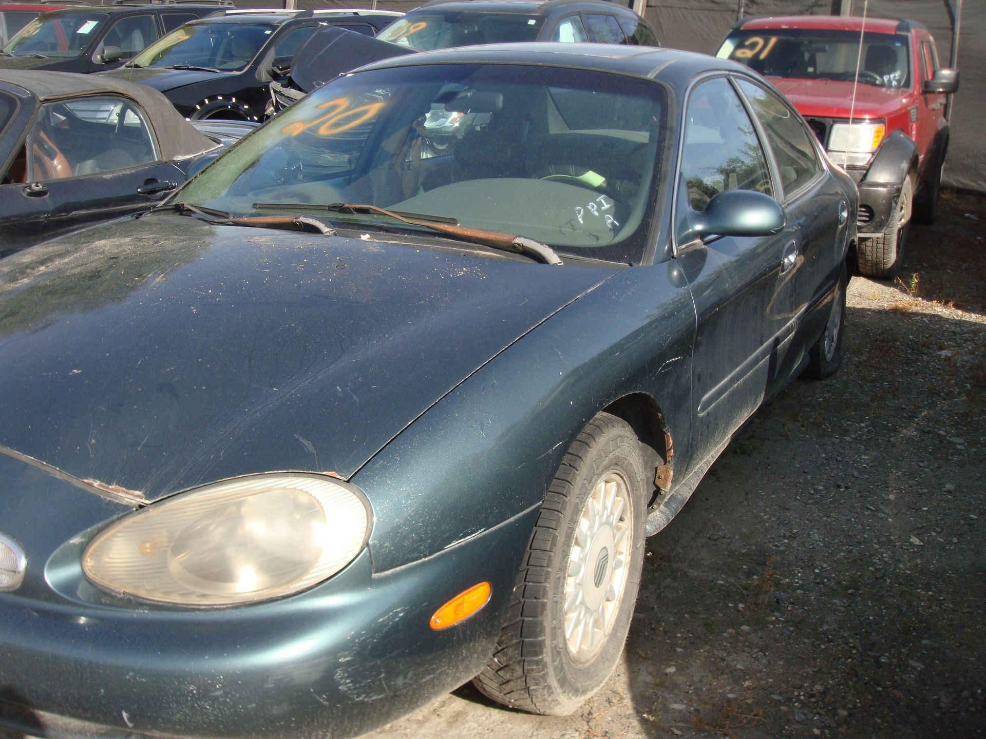 Dark green sedan parked in a crowded lot beside other cars