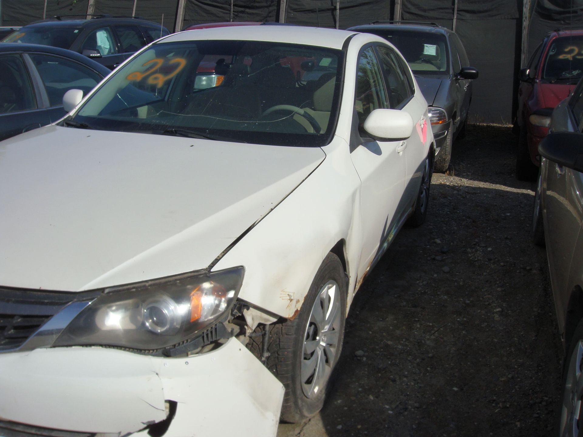 White sedan with front-end damage parked between other cars in a lot