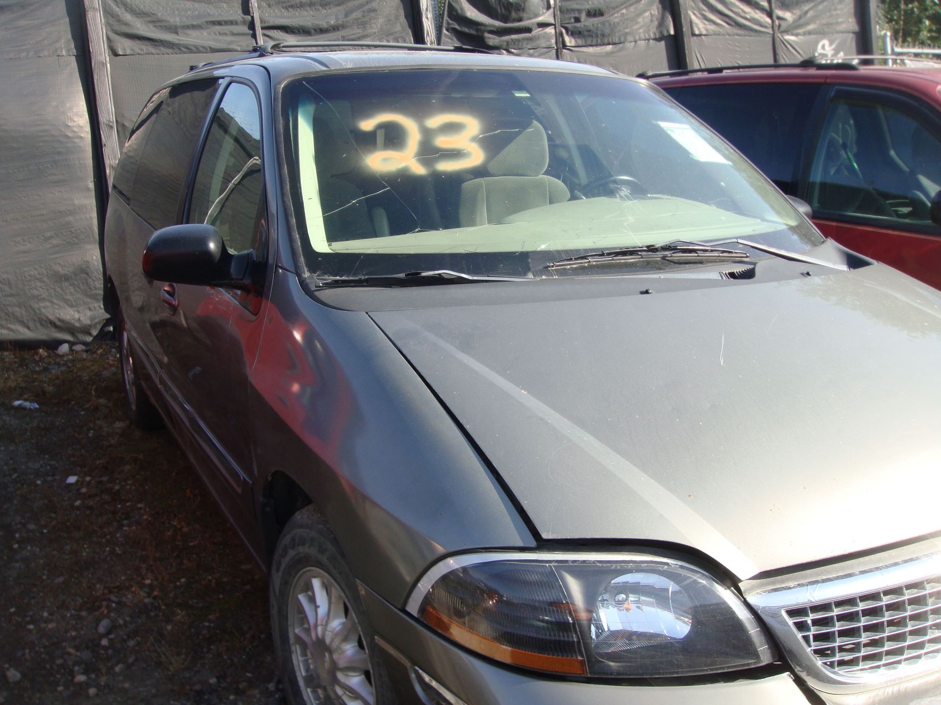 Silver car with a yellow “23” on the windshield, parked beside a red car