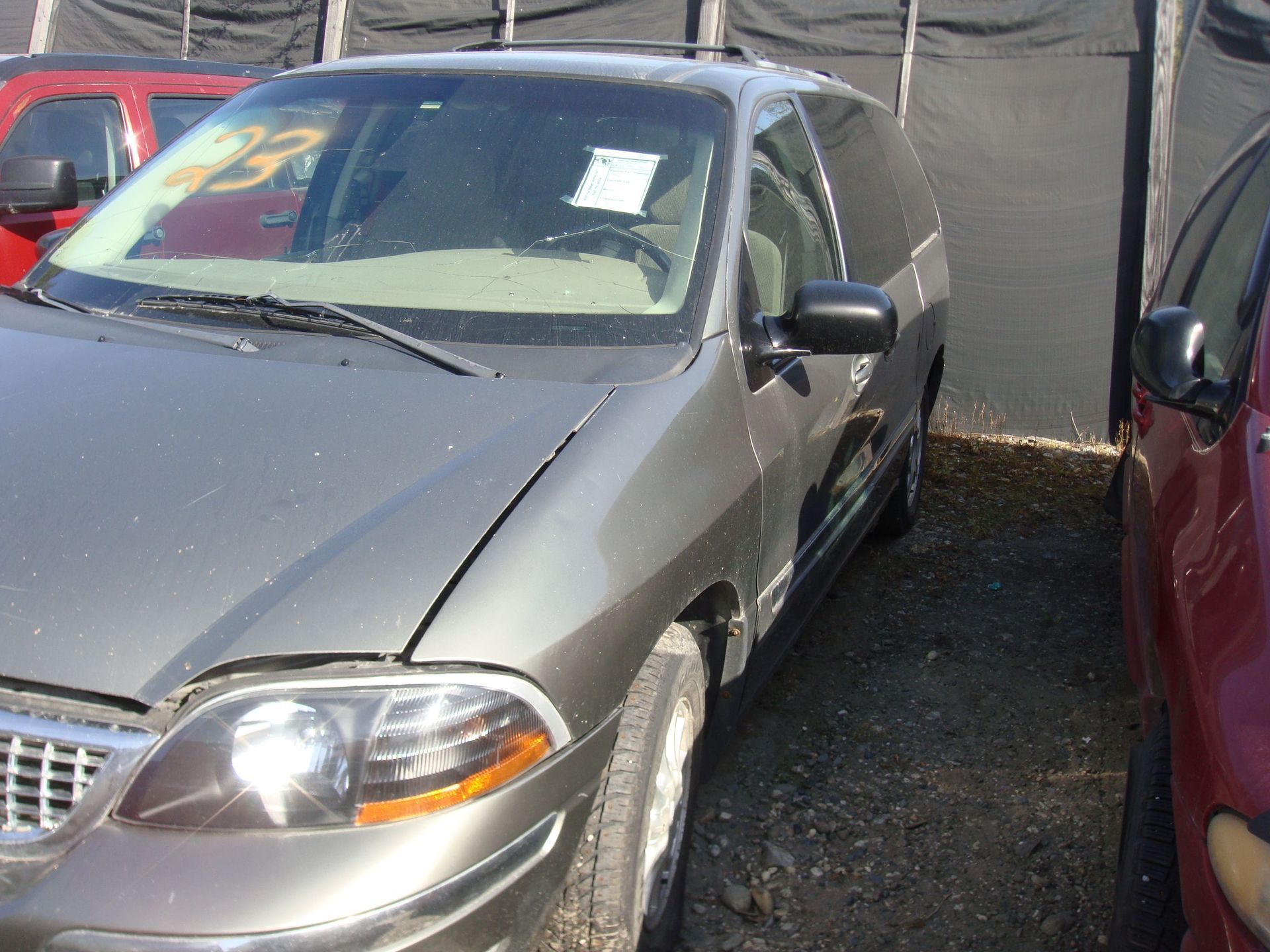 Silver sedan parked between cars on gravel lot