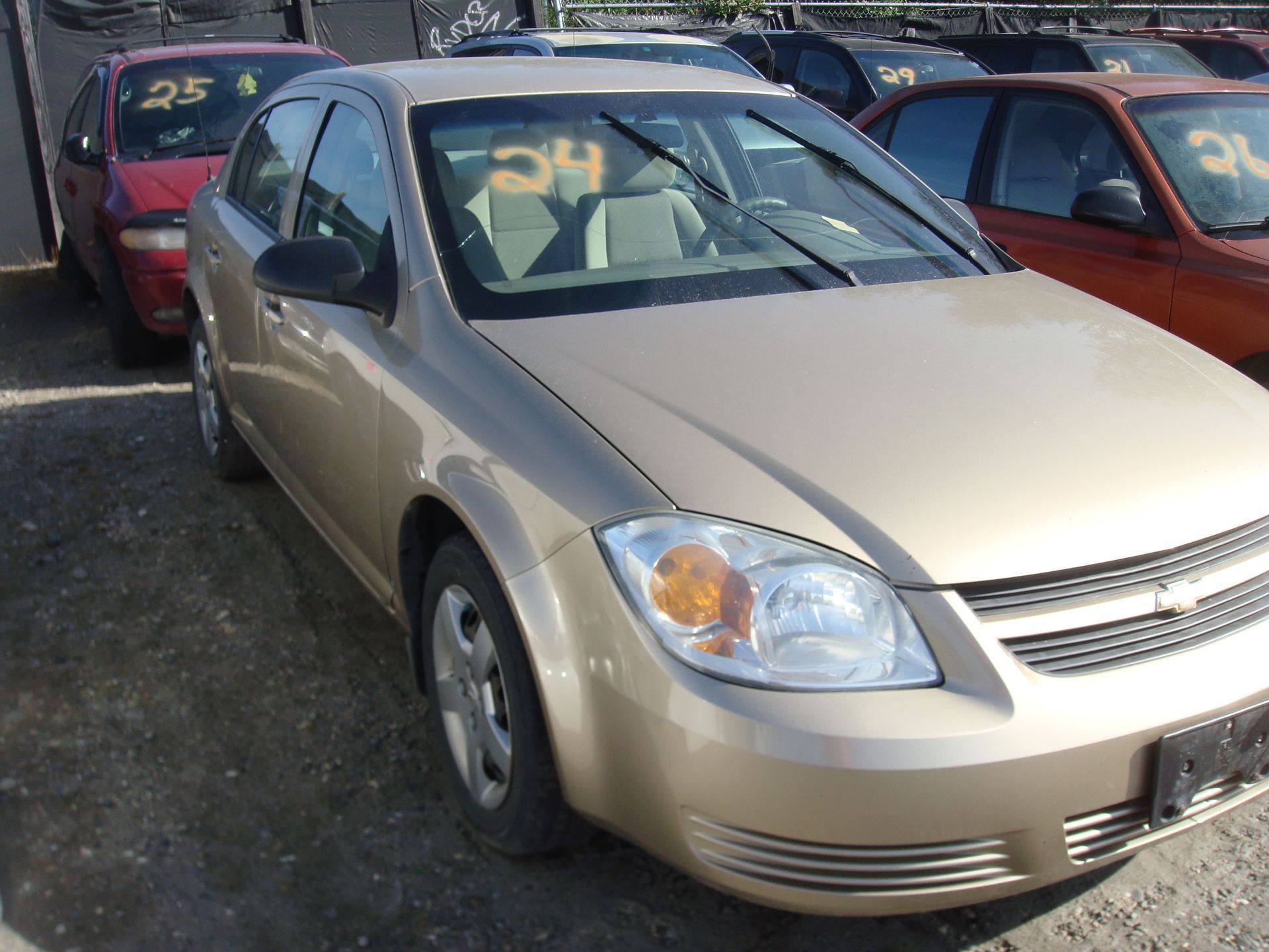 Silver sedan parked in a crowded car lot with red and maroon cars nearby