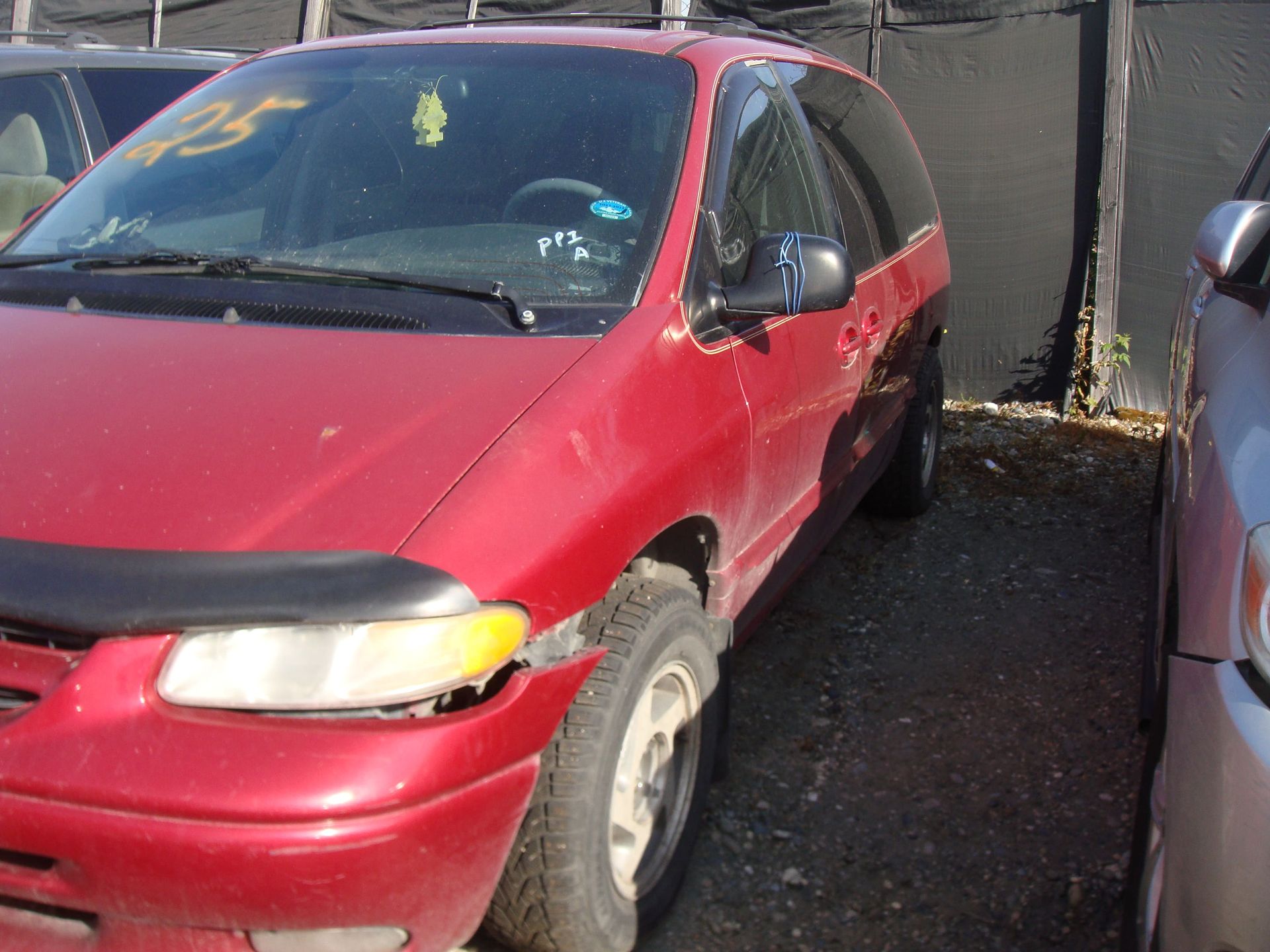 Red minivan parked in a driveway beside a building, front-left view.