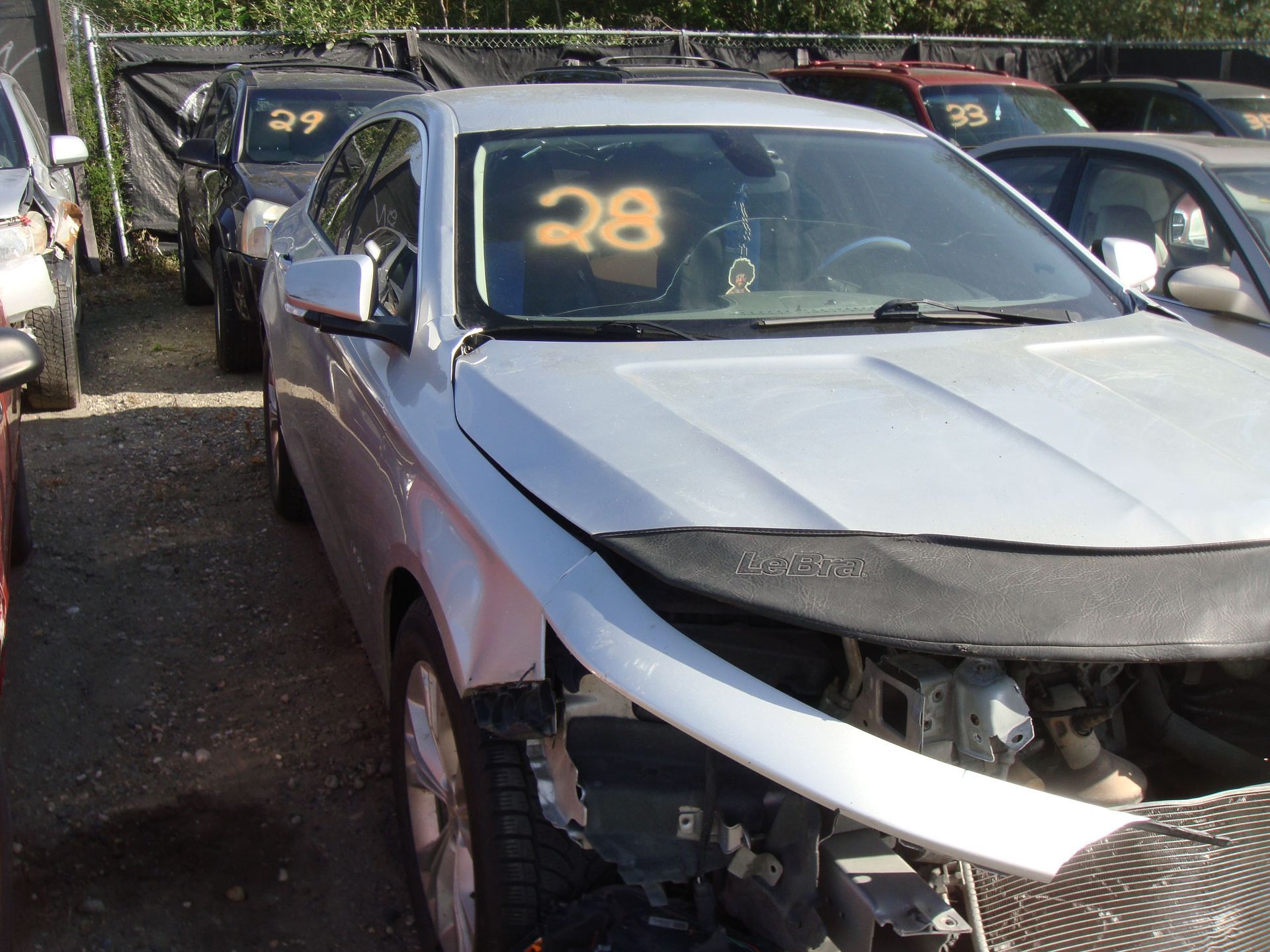 Damaged silver car with a dented front end in a parking lot