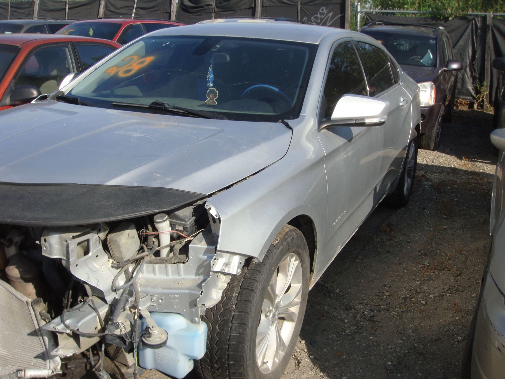Silver sedan with front-end crash damage parked in a lot