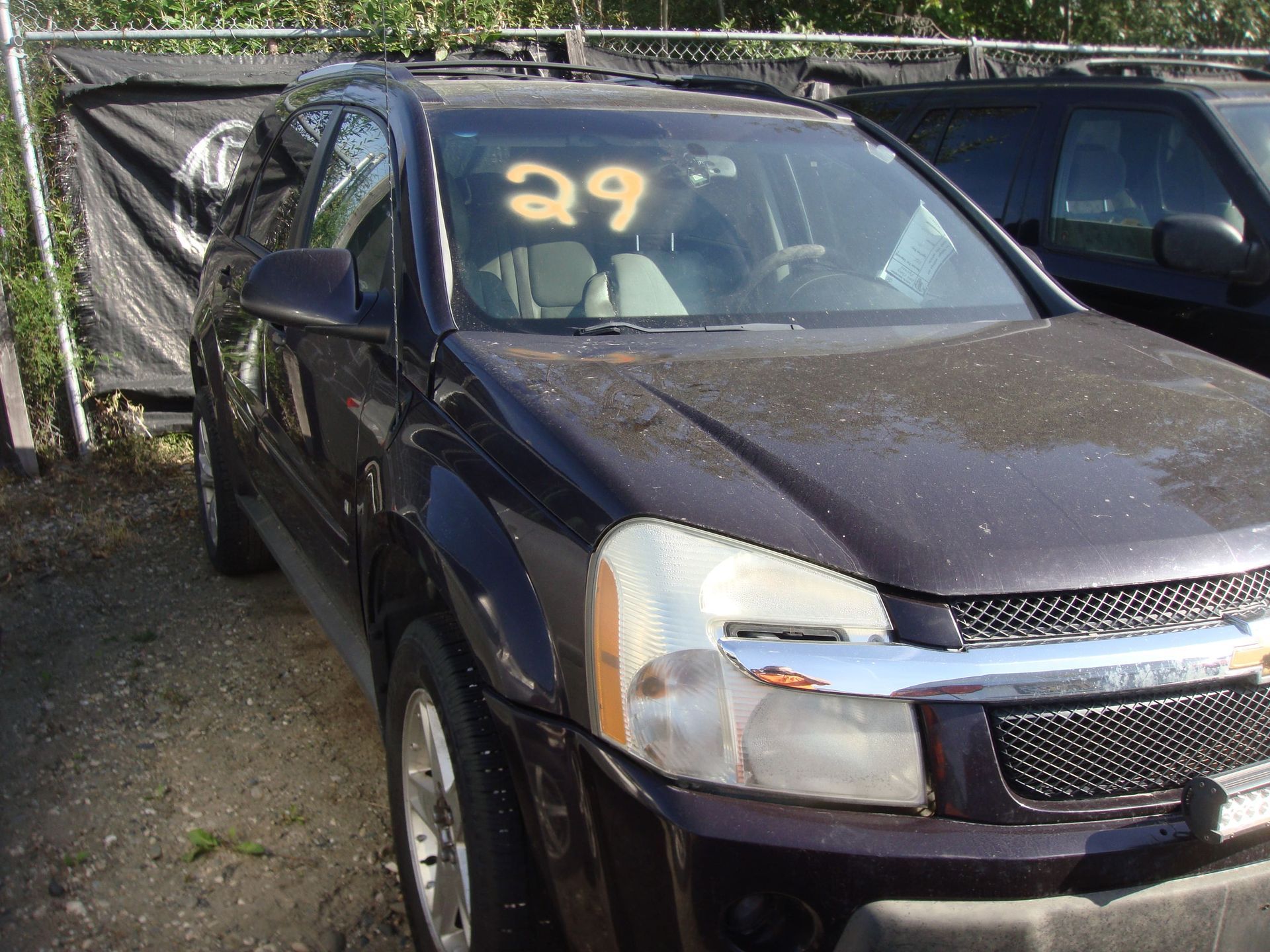 Black SUV with front-end damage, parked beside another vehicle outdoors.