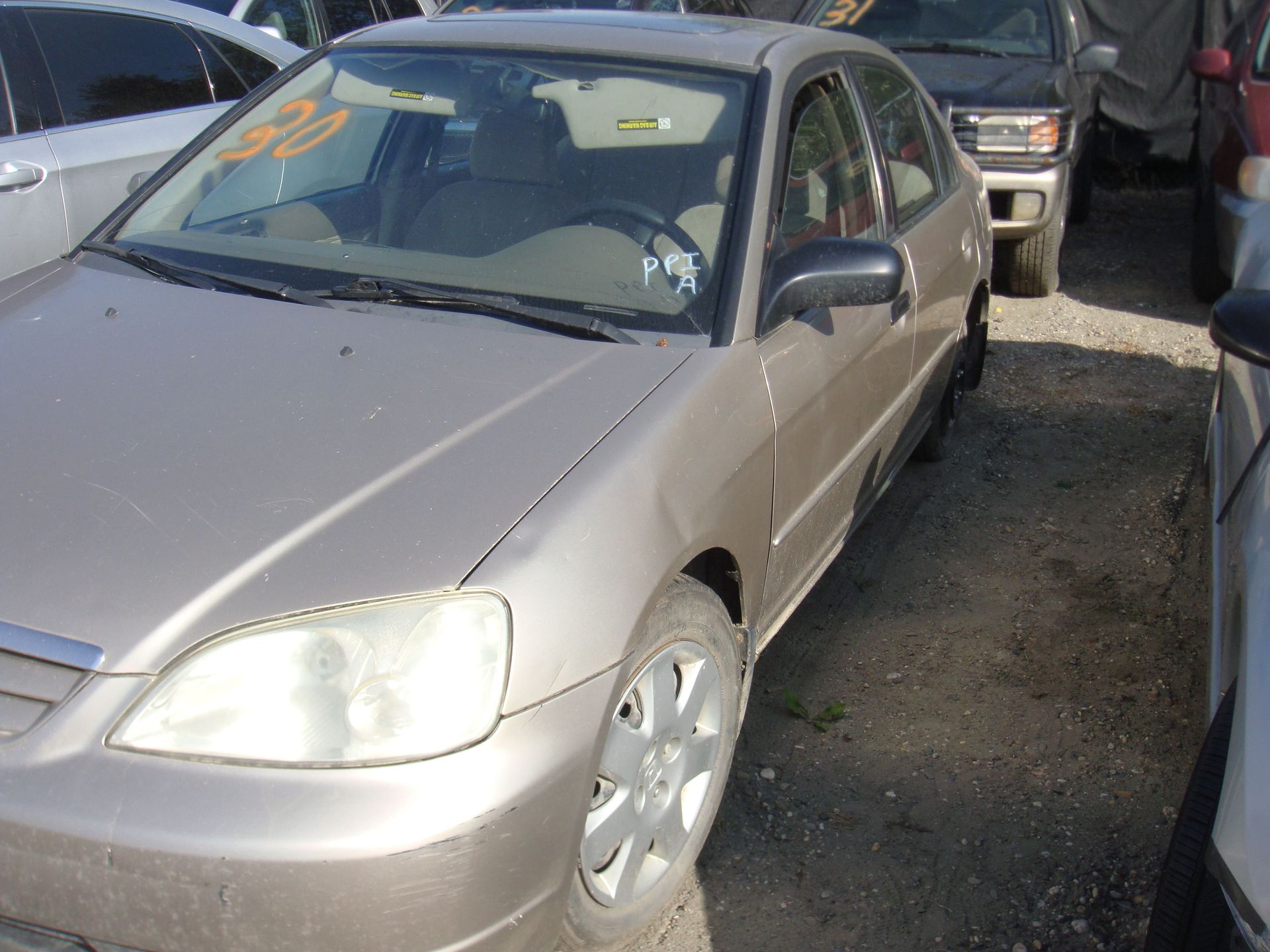 Silver sedan parked in a narrow lot beside other vehicles