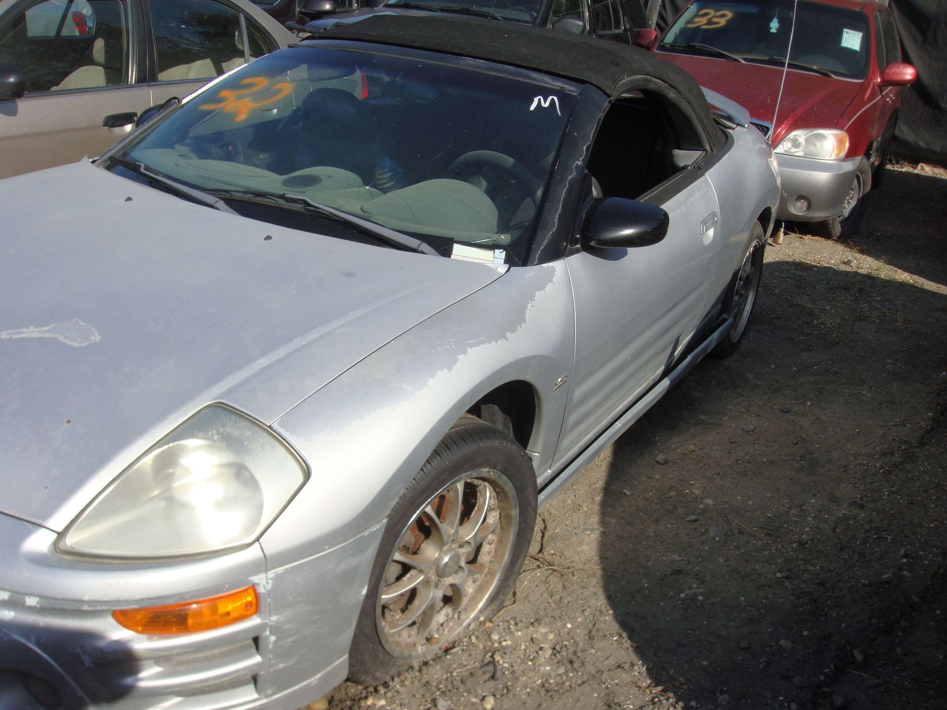 Silver convertible sports car parked on a street, viewed from the front-left side