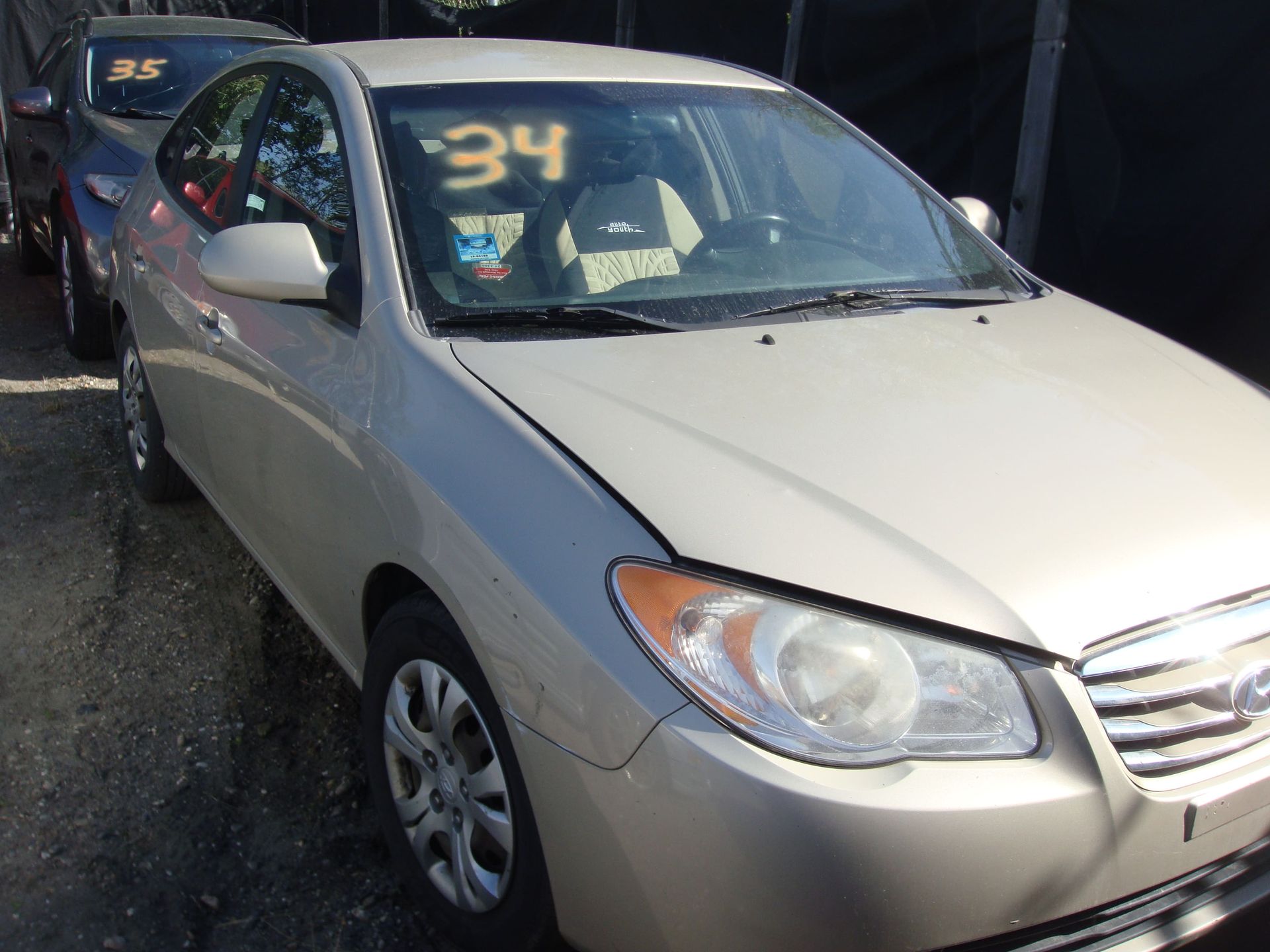 Silver sedan with a windshield sale number, parked outdoors in a car lot