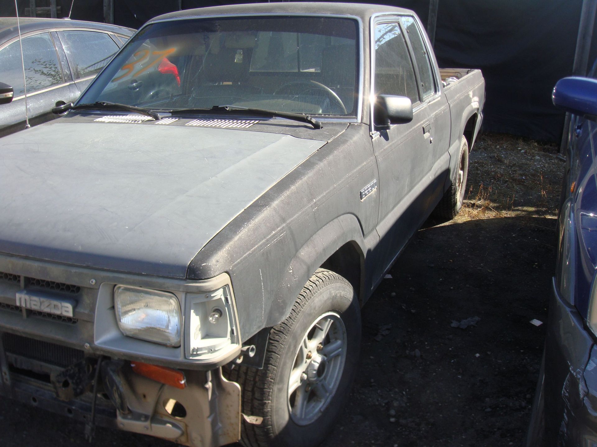 Gray pickup truck parked in a lot, front-left view, with another vehicle beside it.