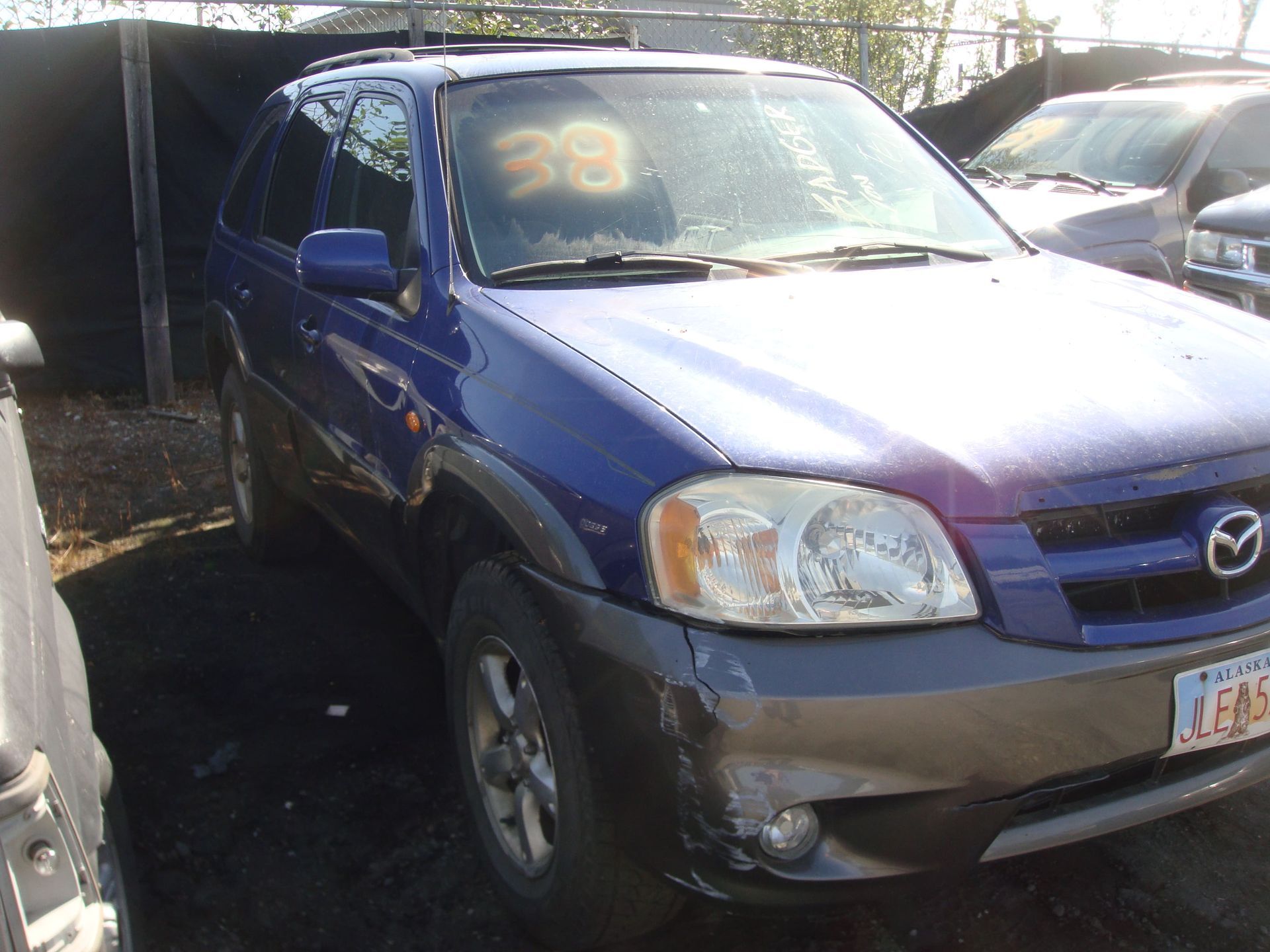 Blue Mazda SUV parked in a lot, front-right view, with minor front-end damage.