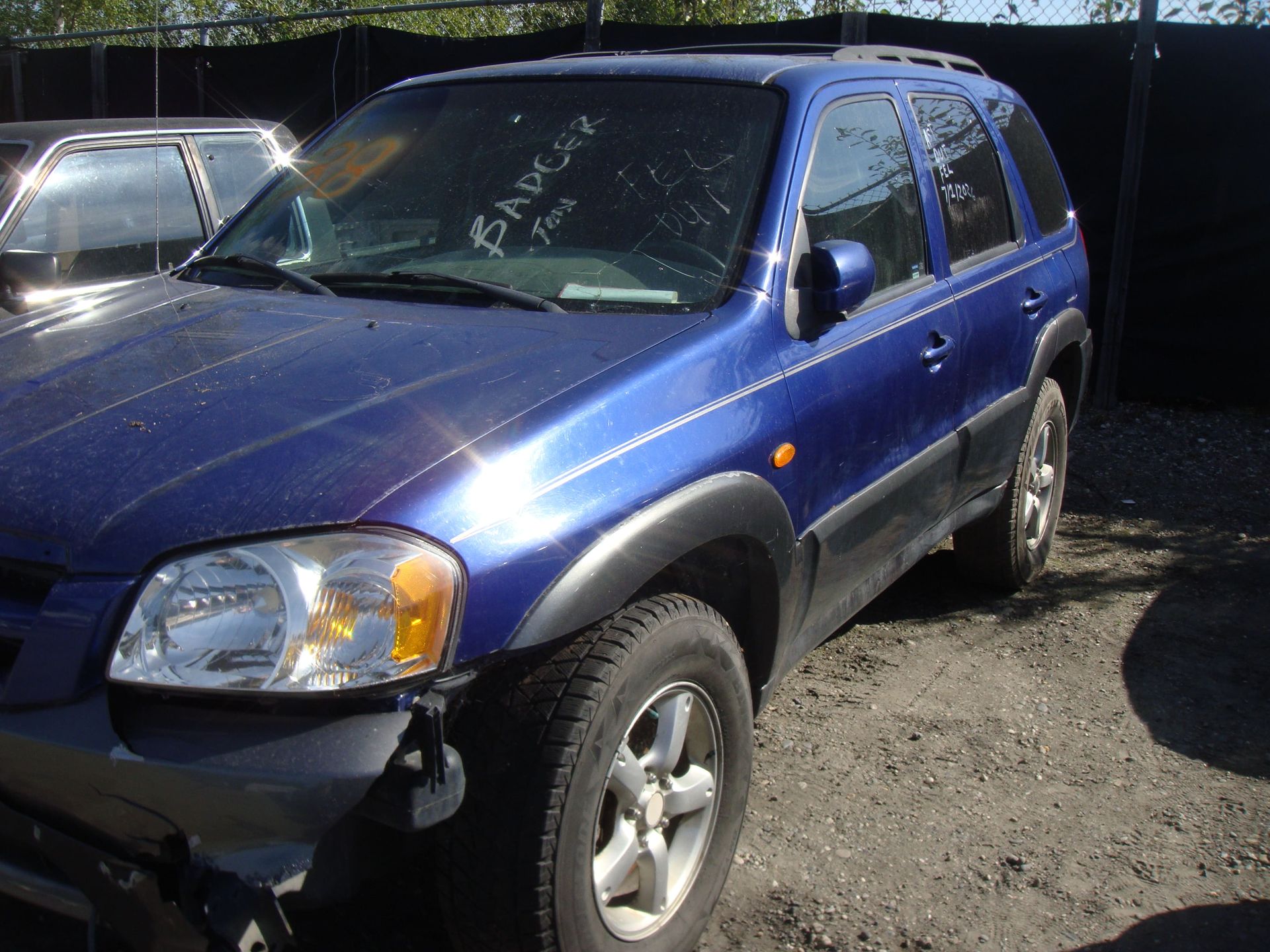 Blue SUV parked in a lot, with visible front-end damage and a dented bumper.