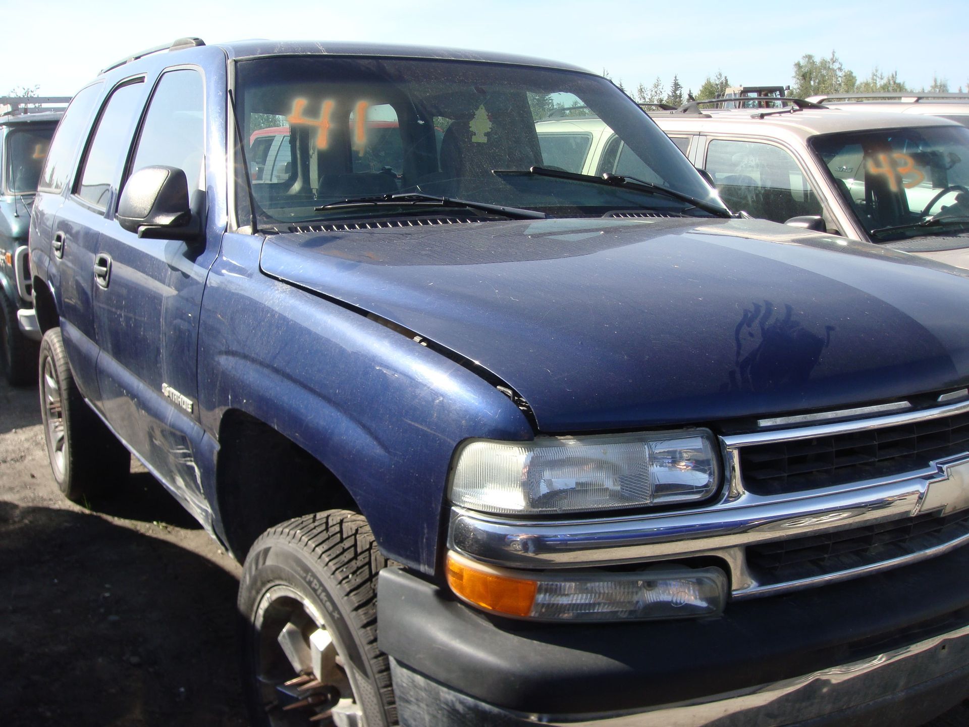 Blue SUV parked in a lot, front-left view with visible hood damage