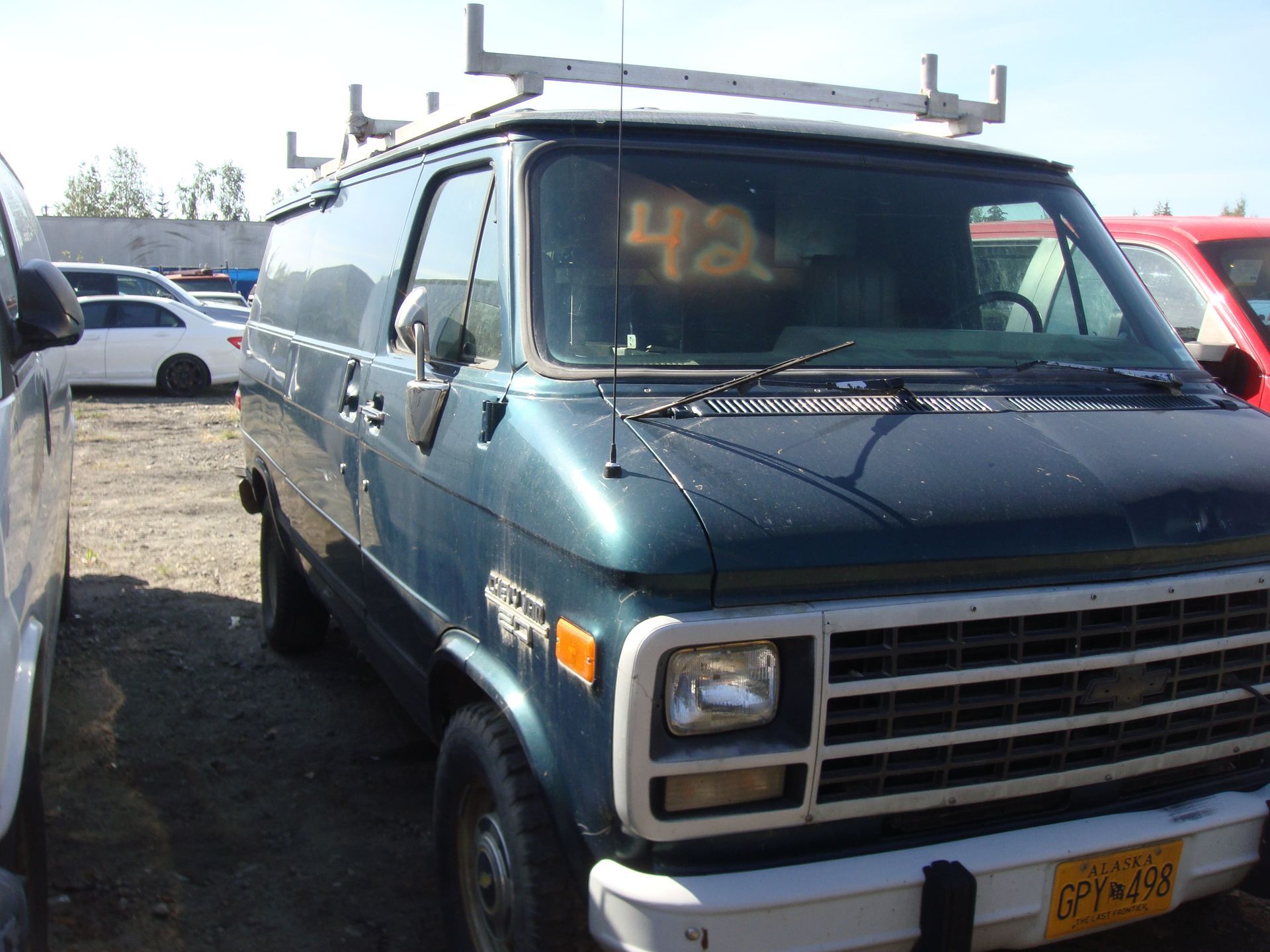 Blue van parked in a lot, front view with roof rack and amber windshield sign