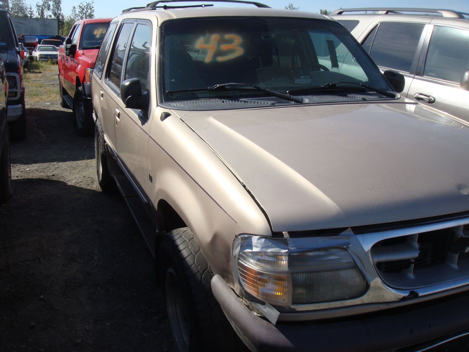 Silver pickup truck parked in a lot, with a red vehicle beside it and a yellow “43” on the windshield