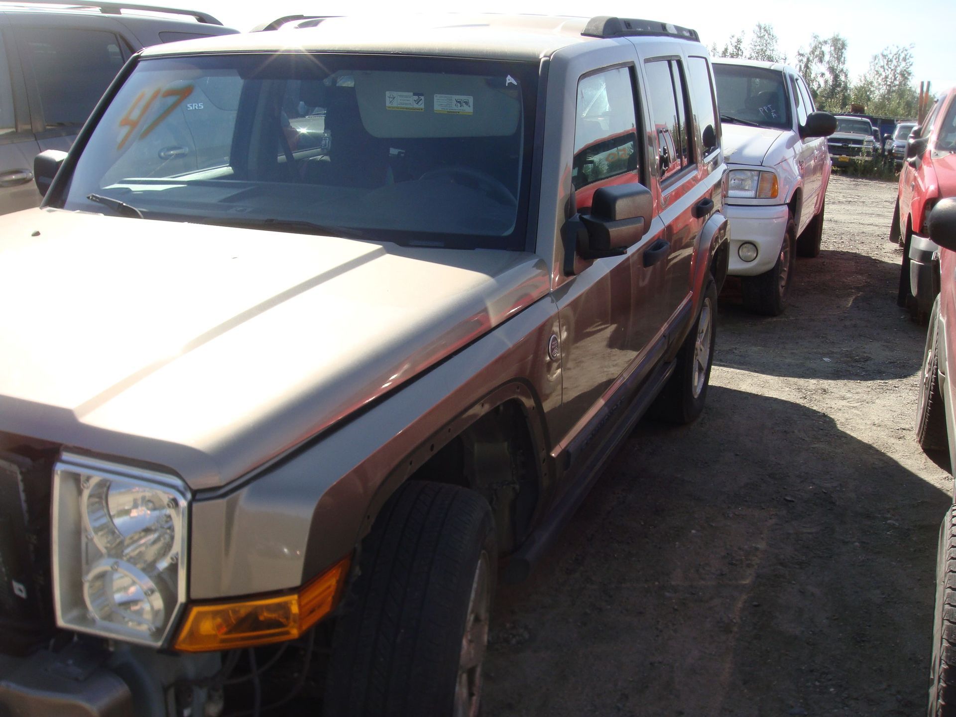 Two tan SUVs parked in a gravel lot, front vehicle angled toward the camera