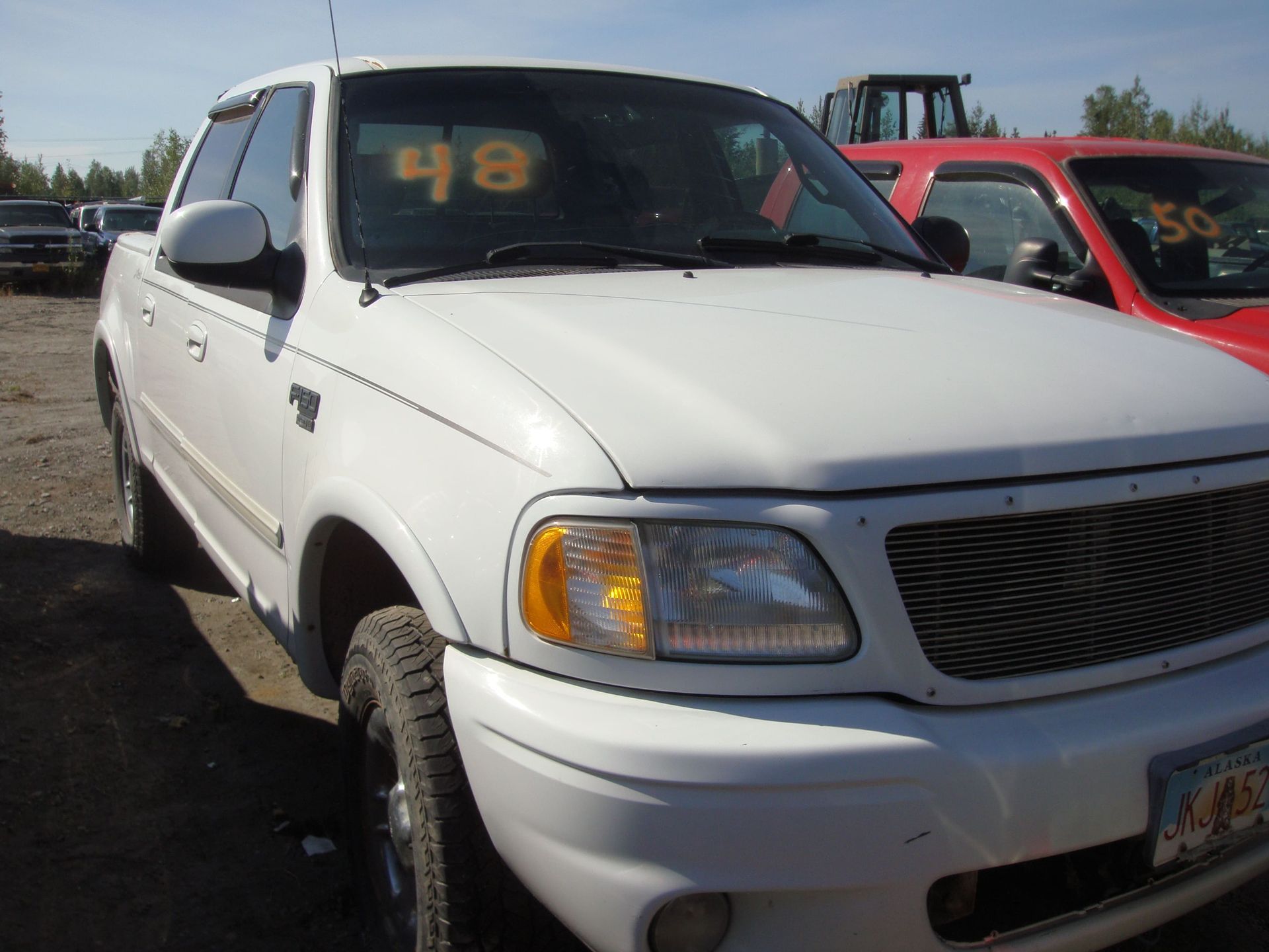 White pickup truck parked outdoors with a red vehicle beside it
