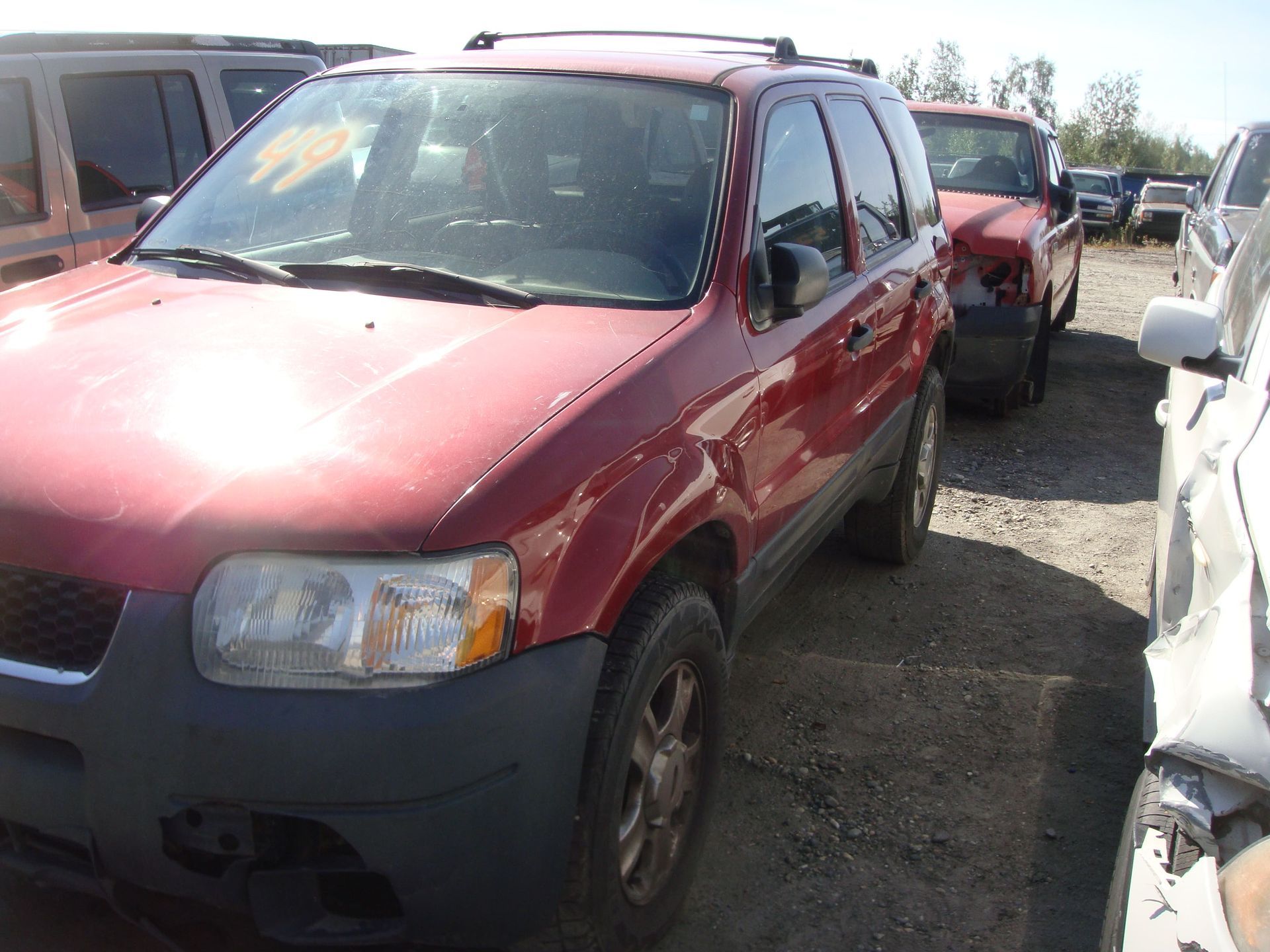 Red SUV parked in a lot beside other vehicles, with a damaged front bumper.