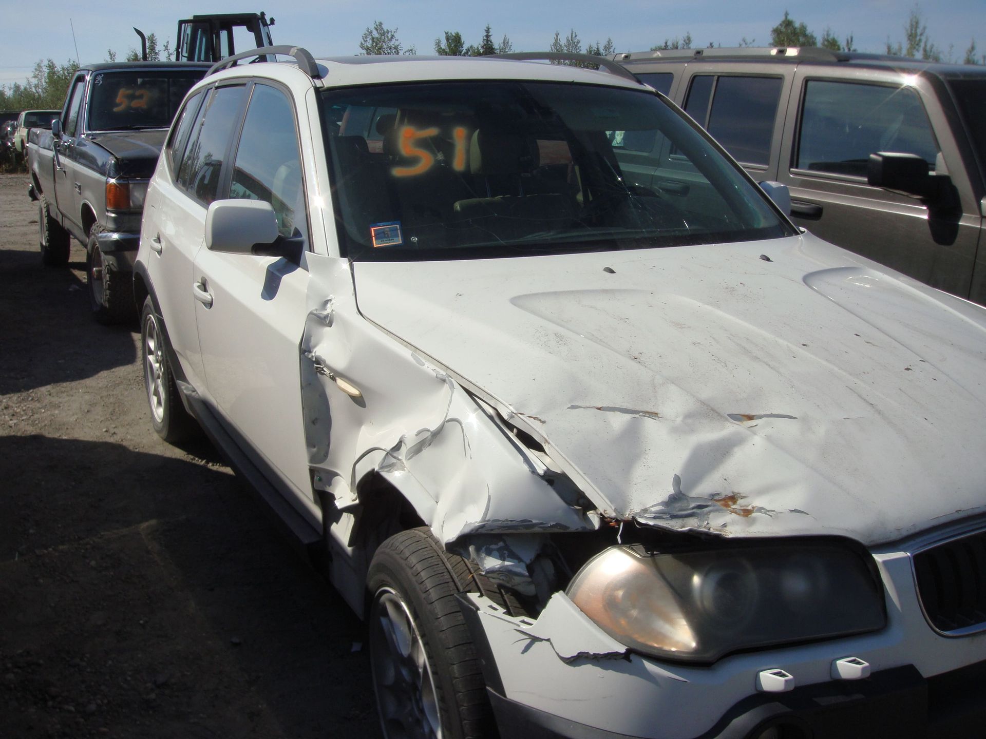 White SUV with severe front-end damage in a parking lot, with other vehicles nearby
