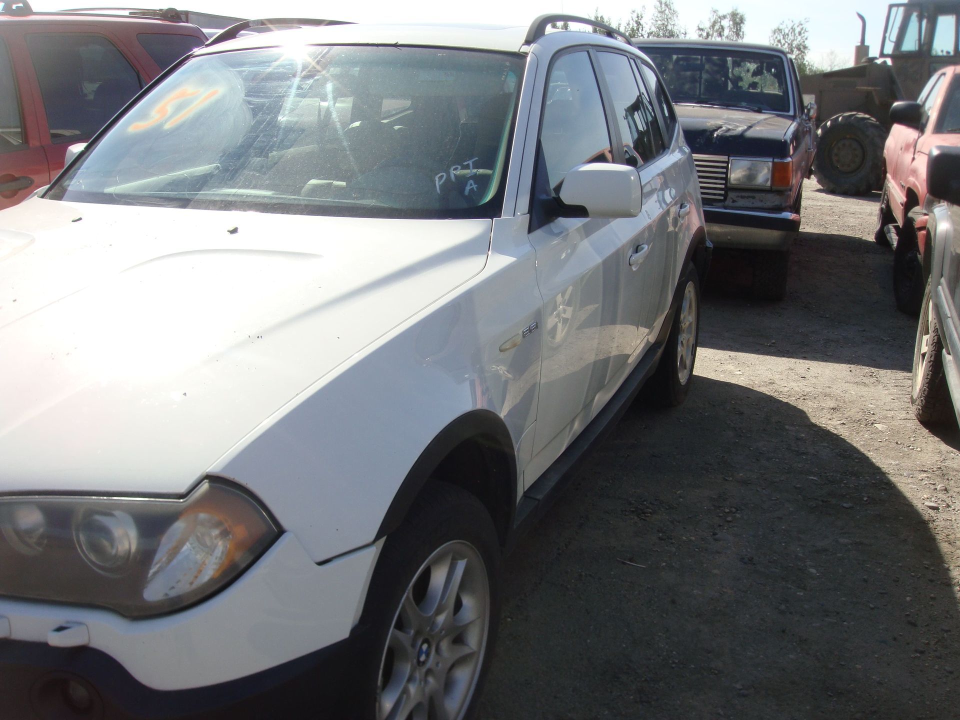 White SUV parked in a gravel lot with other vehicles nearby