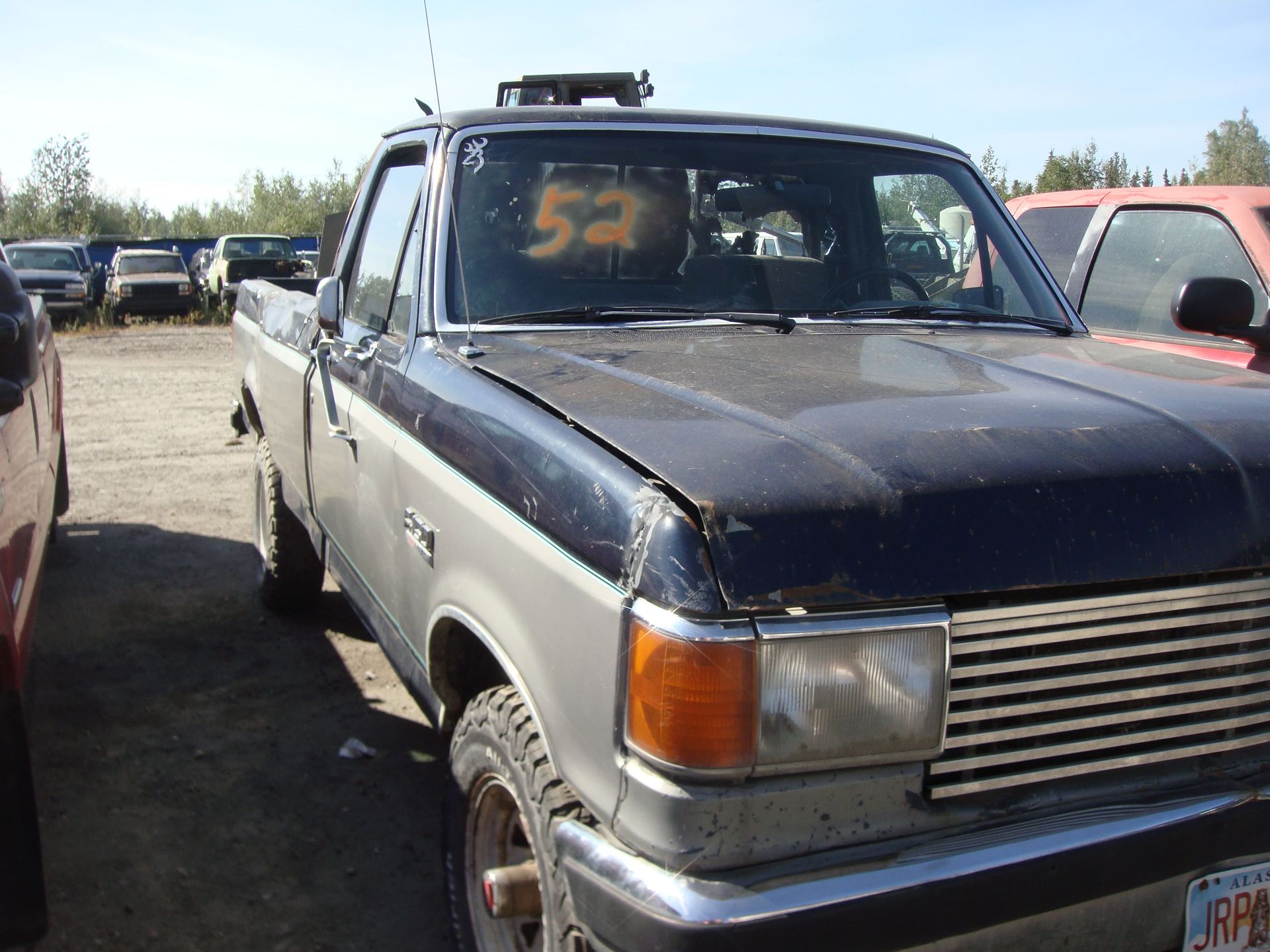 Blue pickup truck parked in a lot, with orange number 52 on the windshield.