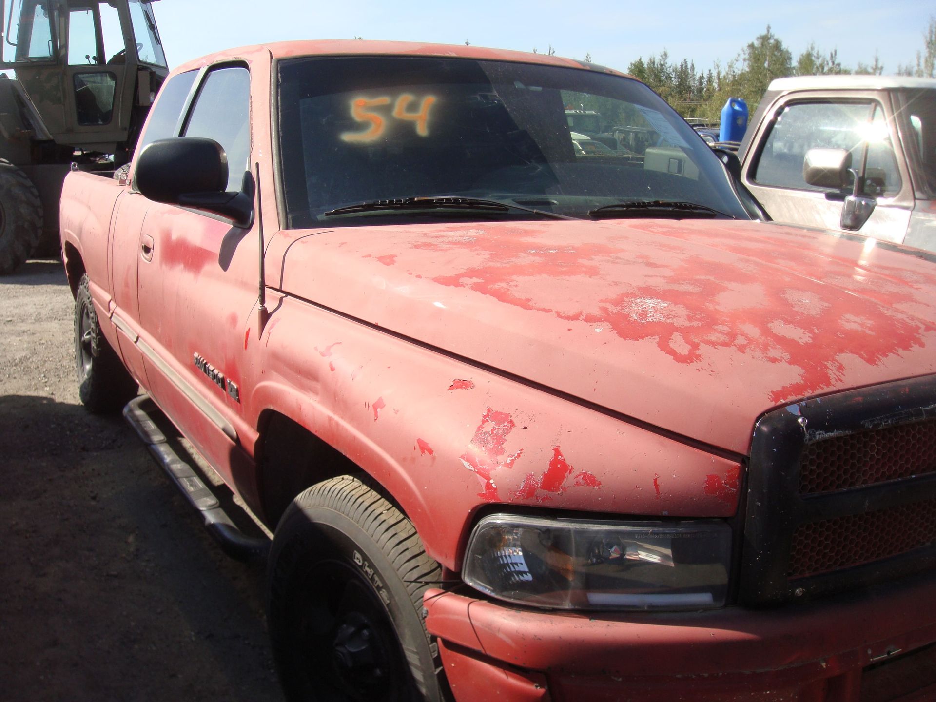 Red pickup truck with faded red paint parked outdoors, number 54 marked on the windshield.