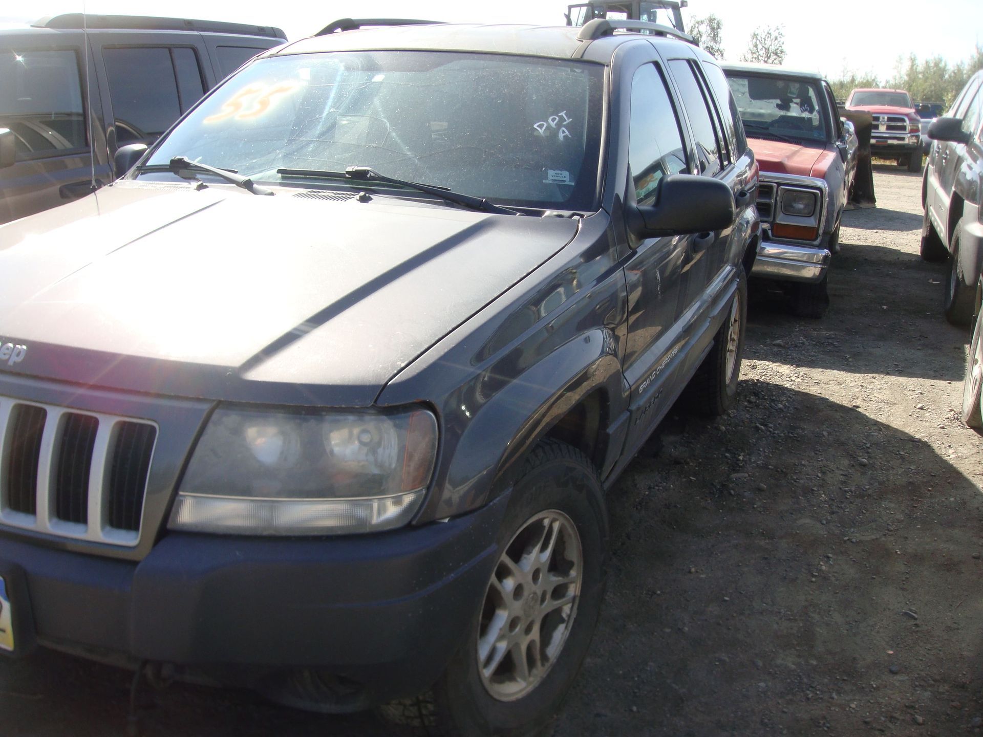 Blue SUV parked in a gravel lot, front view with other vehicles nearby