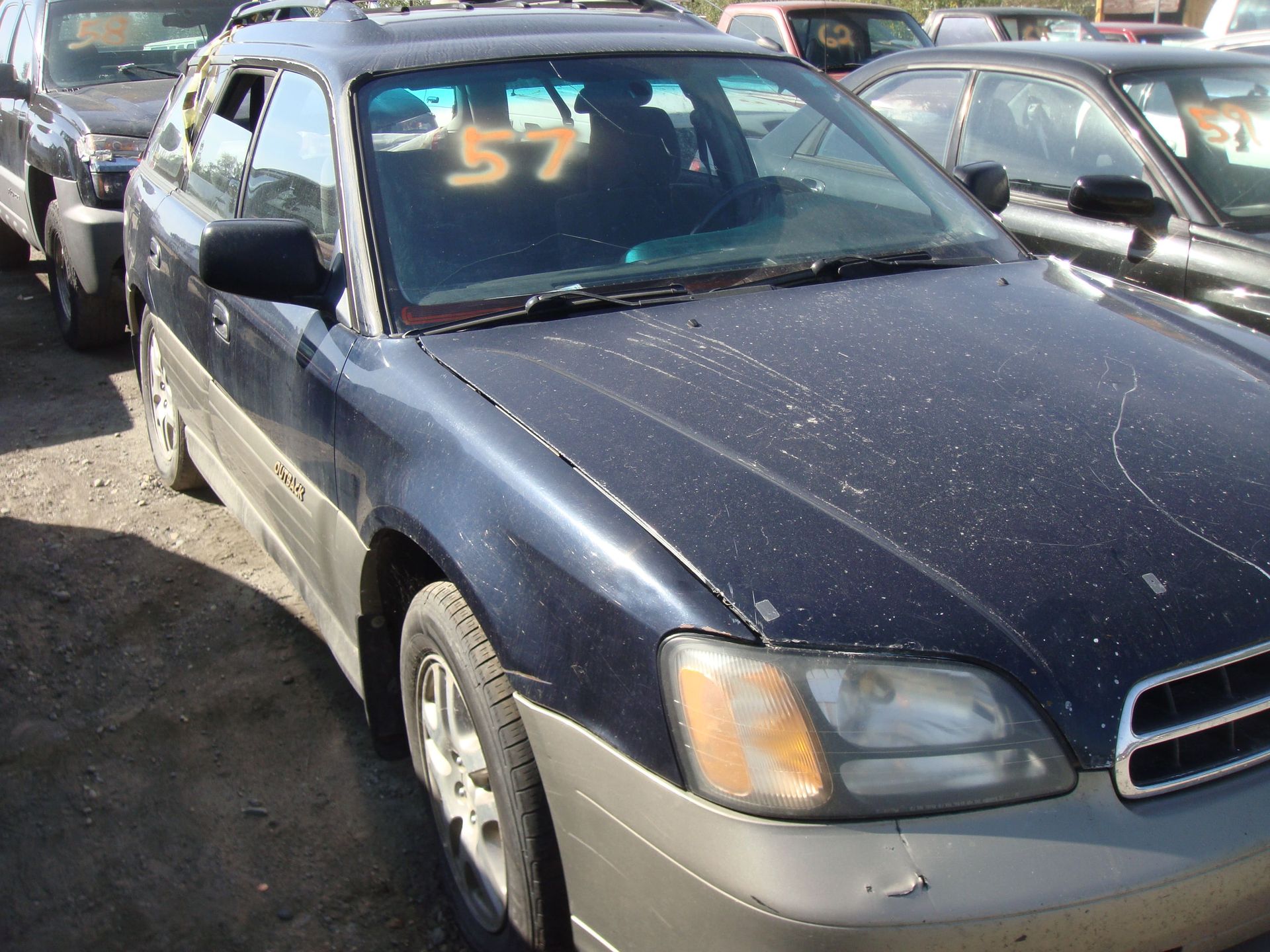 Blue sedan in a car lot with a yellow “57” on the windshield
