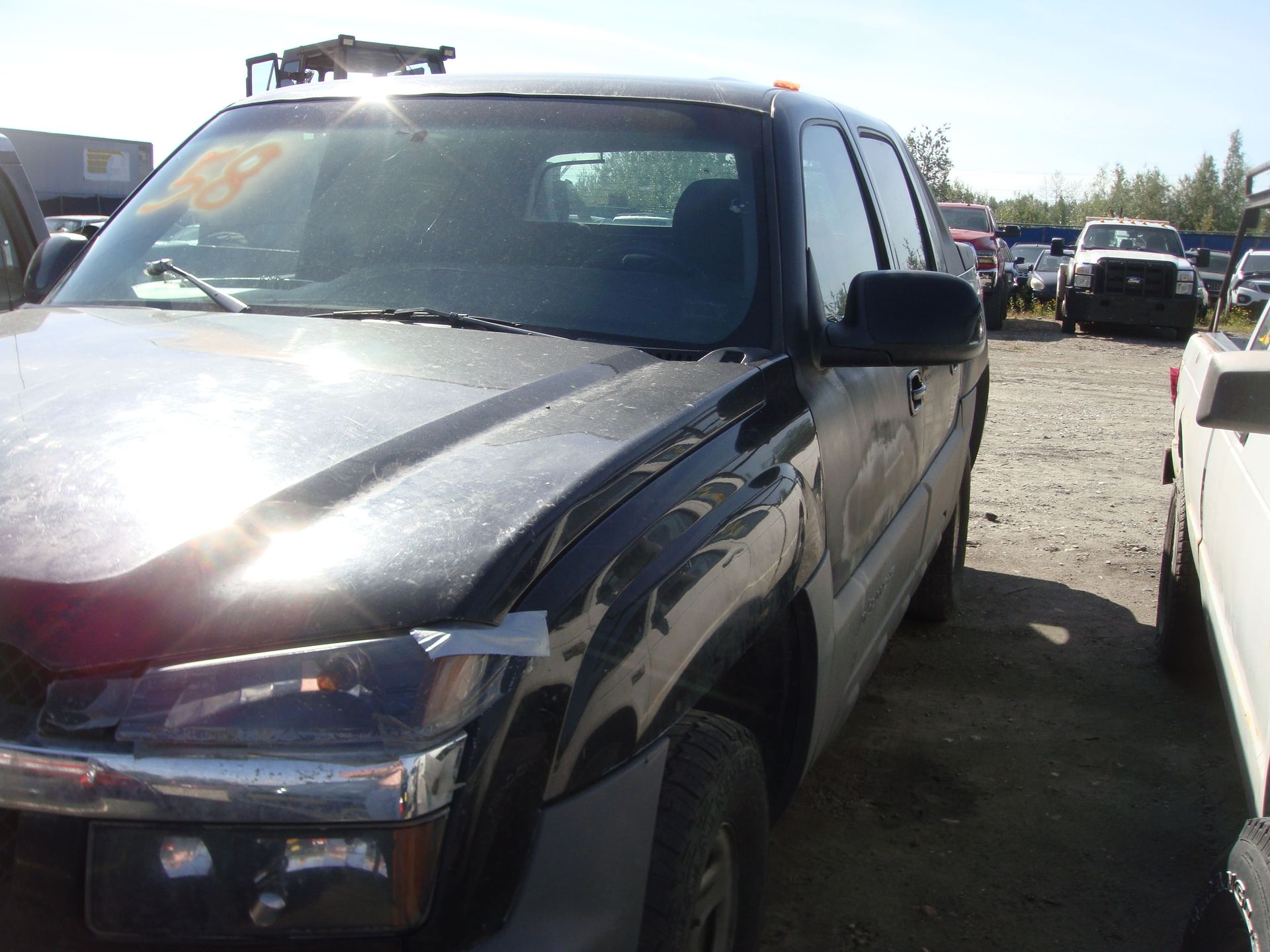 Black SUV parked in a lot, front view with sunlight glare on the hood