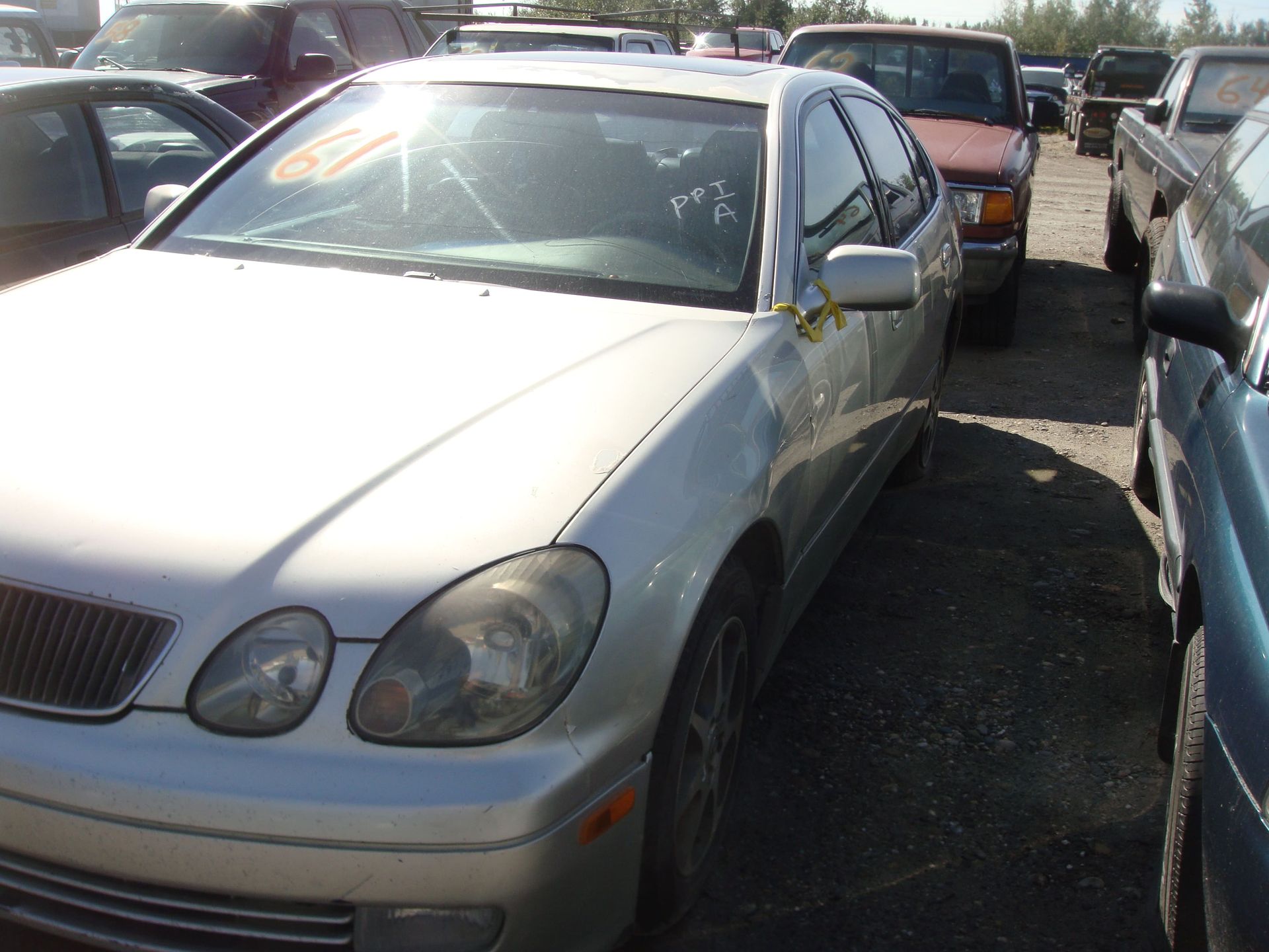 Silver sedan parked tightly between other cars in a crowded lot.
