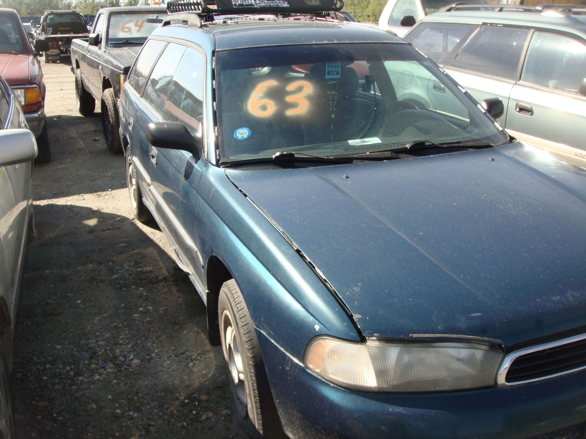 Blue sedan with a large yellow “63” on the windshield parked in a crowded lot