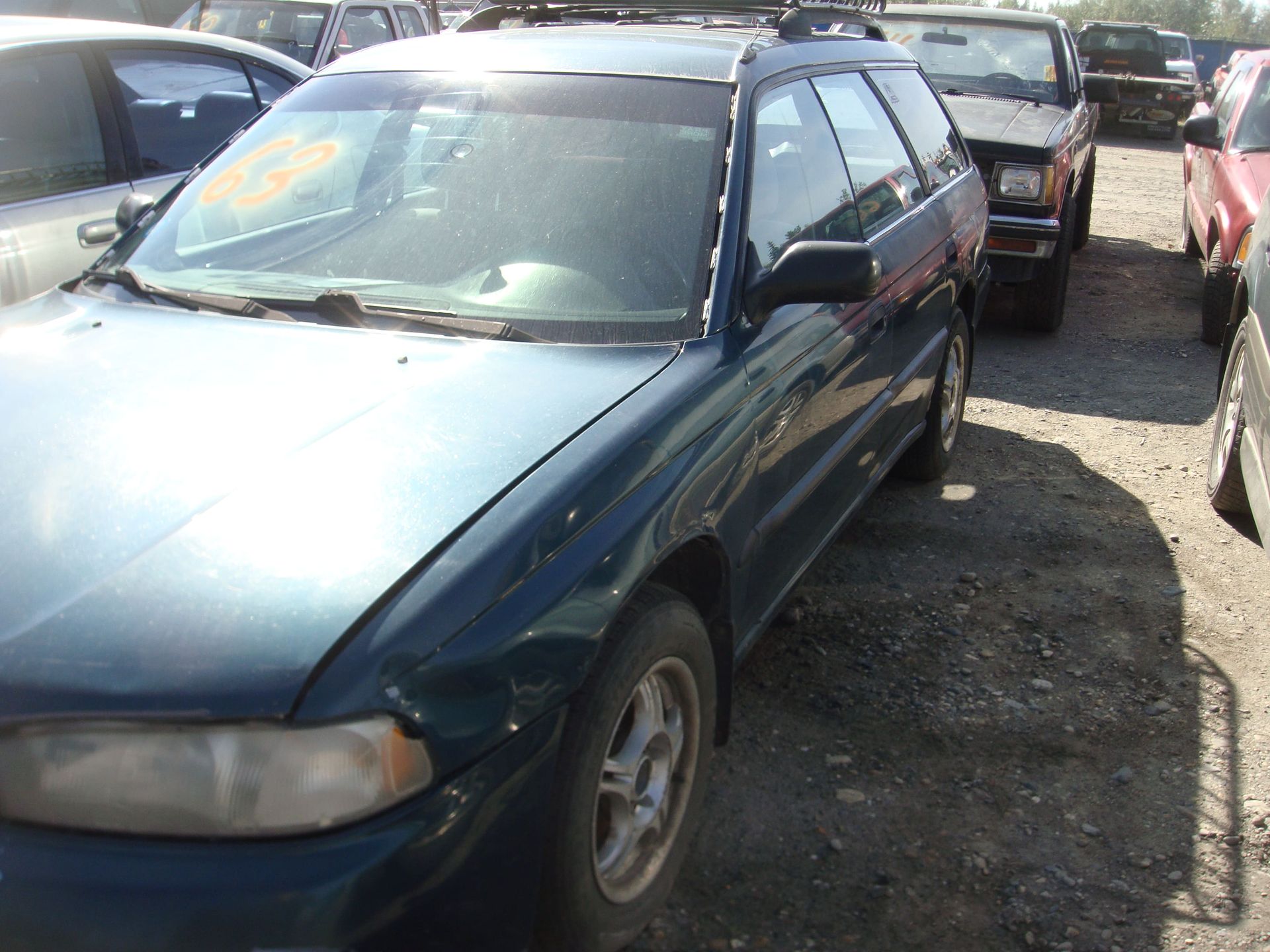 Blue hatchback parked in a crowded lot with other cars nearby