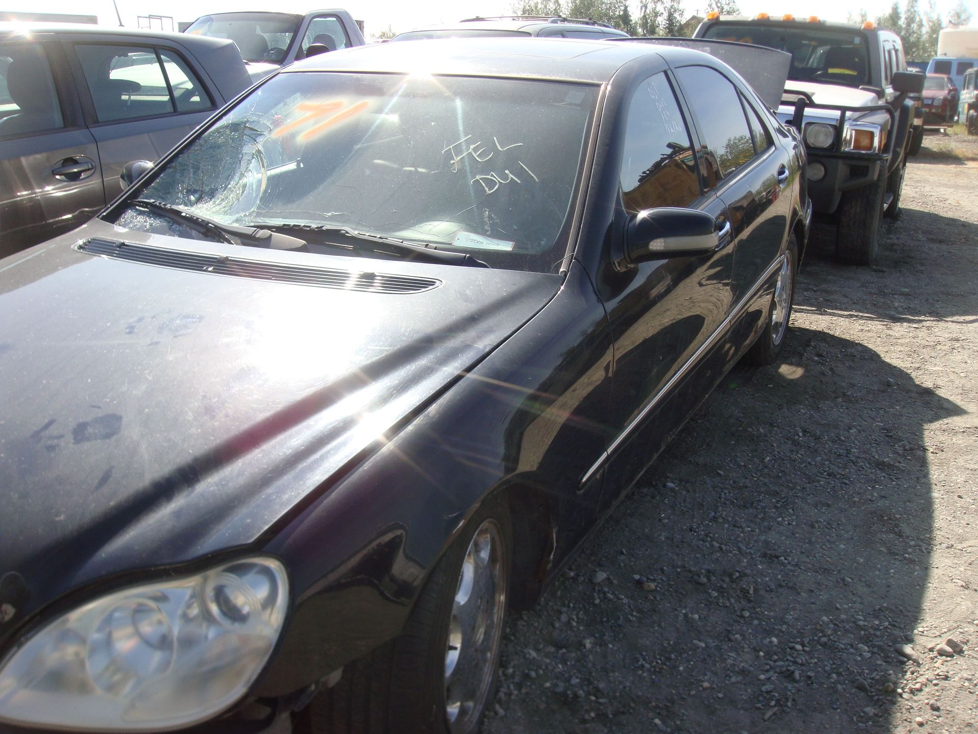 Black sedan with a shattered windshield parked in a lot