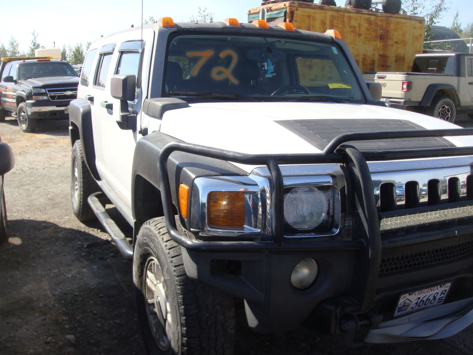 White SUV with black bull bar parked in a lot, front view with orange writing on windshield
