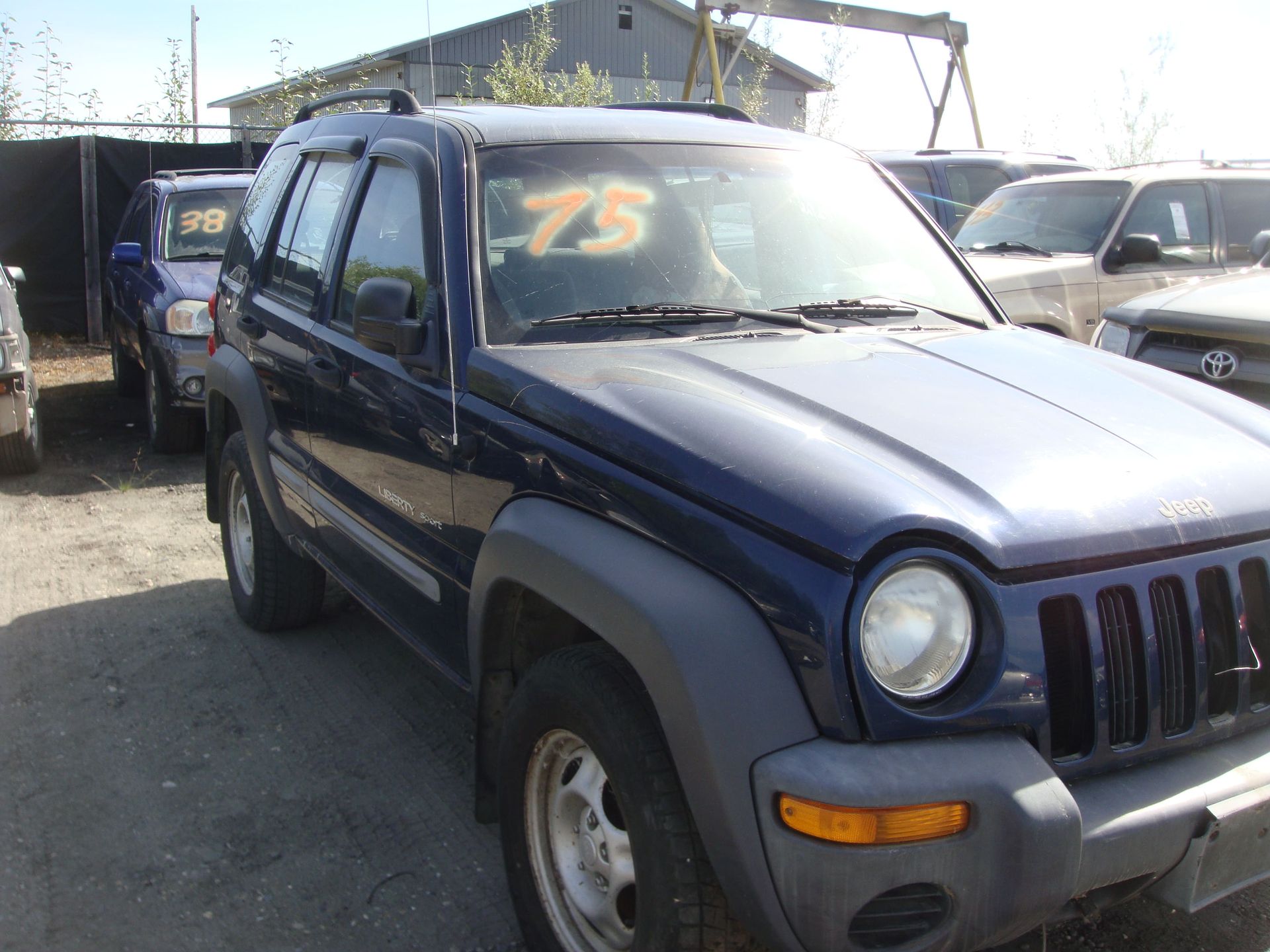 Blue SUV parked in a lot, with orange “75” written on the windshield.