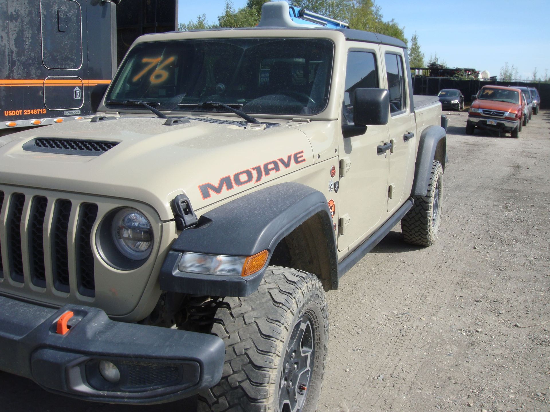 White Jeep Gladiator with MOJAVE decal parked on dirt road at an off-road event