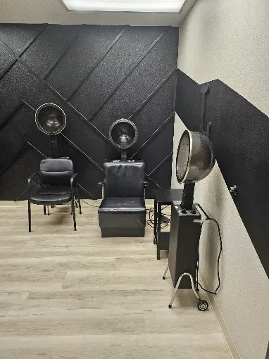 Small salon room with three styling chairs, hooded dryers, and black diamond-patterned wall panels.