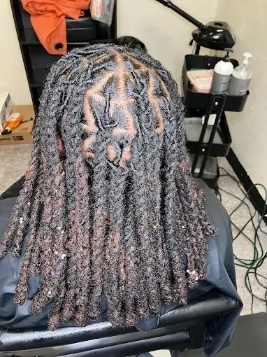 Long dark braided hair styled in medium-length twists, shown from the back in a salon chair.