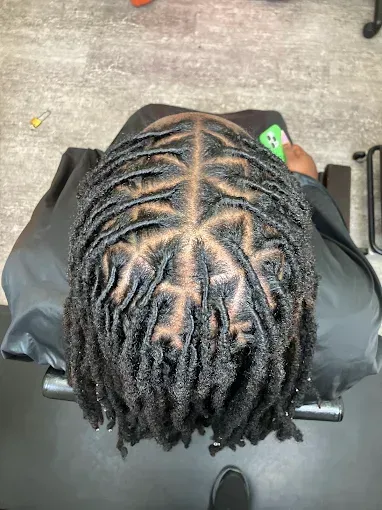 Top-down view of neat scalp braids on a person seated in a salon chair