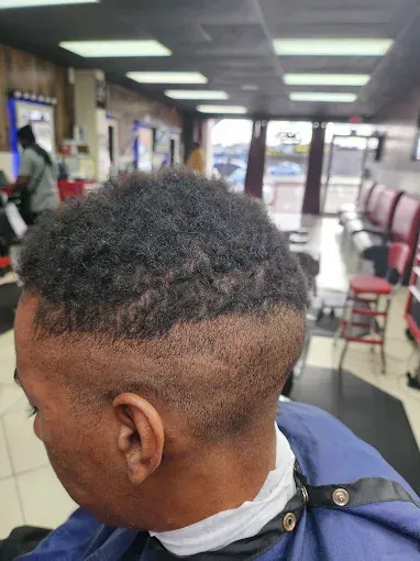 Close-up of a short curly haircut with a fade in a barbershop chair, showing the back and side of the head